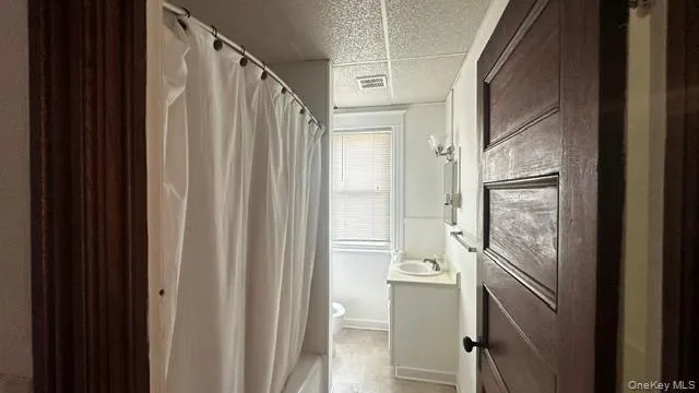 Bathroom featuring a built-in tub with shower, single vanity with a basin sink, wall-mounted light fixture. Bathroom featuring a built-in tub with shower, single vanity with a basin sink, wall-mounted light fixture.