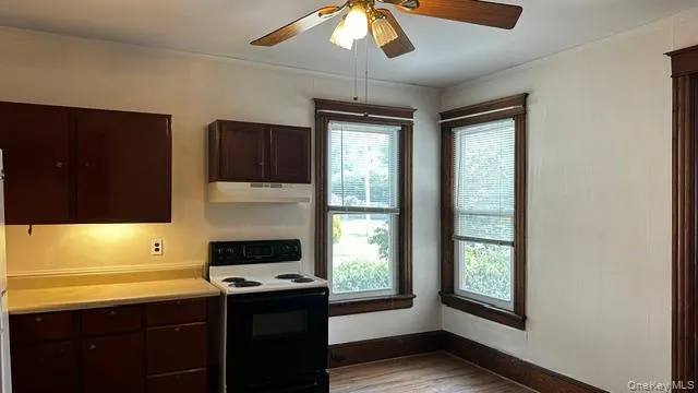 Kitchen area featuring wood-finish cabinetry, a freestanding electric range, and a ceiling fan with integrated lighting Kitchen area featuring wood-finish cabinetry, a freestanding electric range, and a ceiling fan with integrated lighting