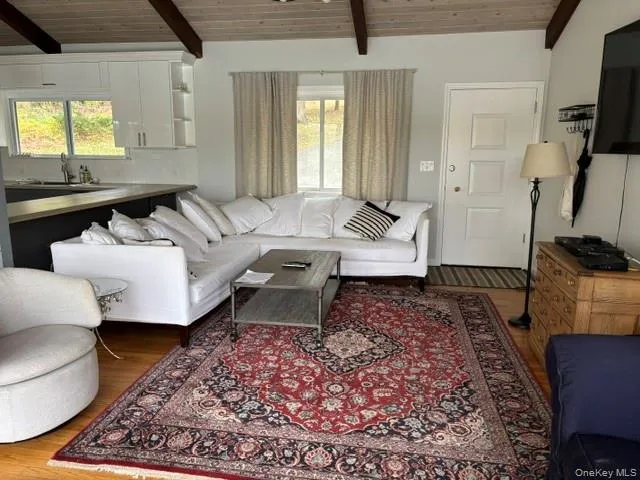 Living room featuring wood finished floors and a wood ceiling with exposed beams Living room featuring wood finished floors and a wood ceiling with exposed beams