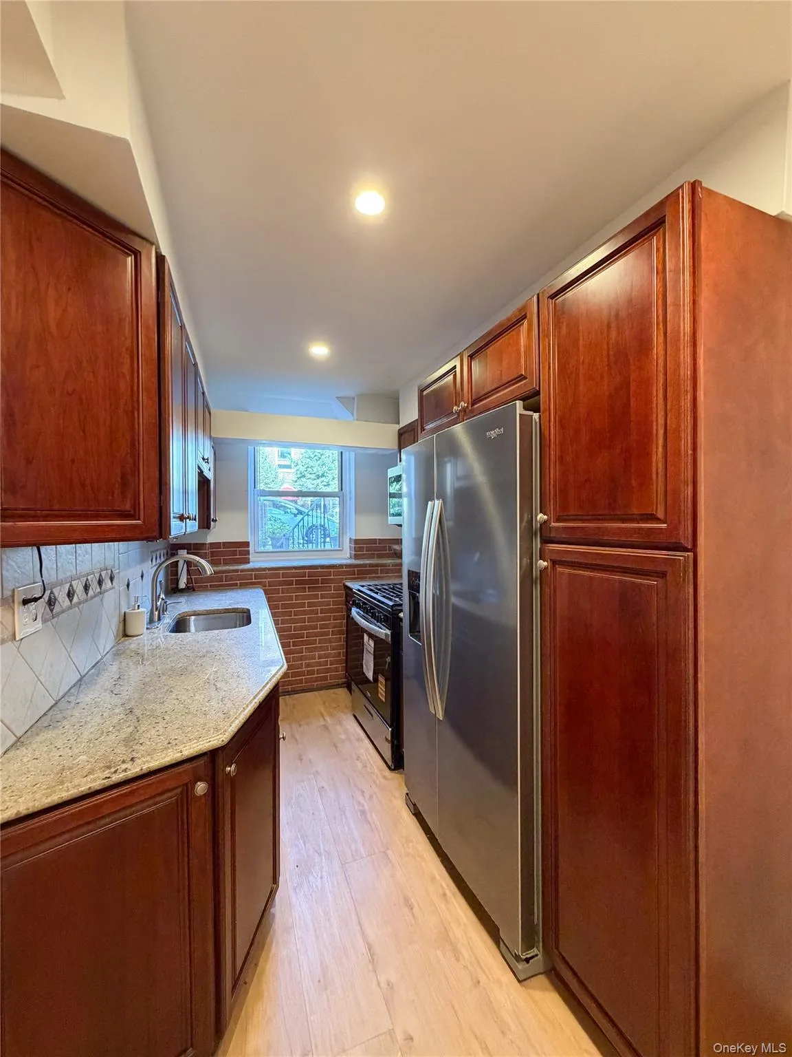 Kitchen featuring wood-finish cabinetry, light-toned countertops, and a full-size stainless steel refrigerator Kitchen featuring wood-finish cabinetry, light-toned countertops, and a full-size stainless steel refrigerator
