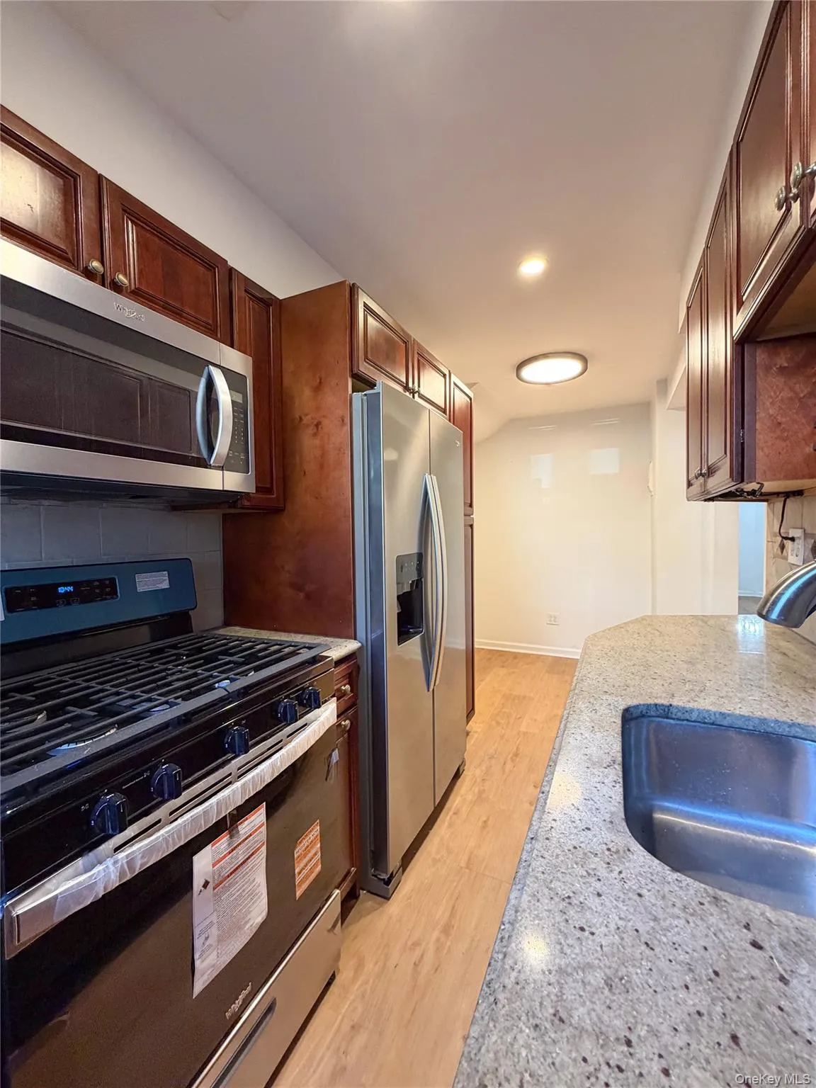 Kitchen featuring wood-finish cabinetry, new stainless steel appliances, and an undermount sink Kitchen featuring wood-finish cabinetry, new stainless steel appliances, and an undermount sink