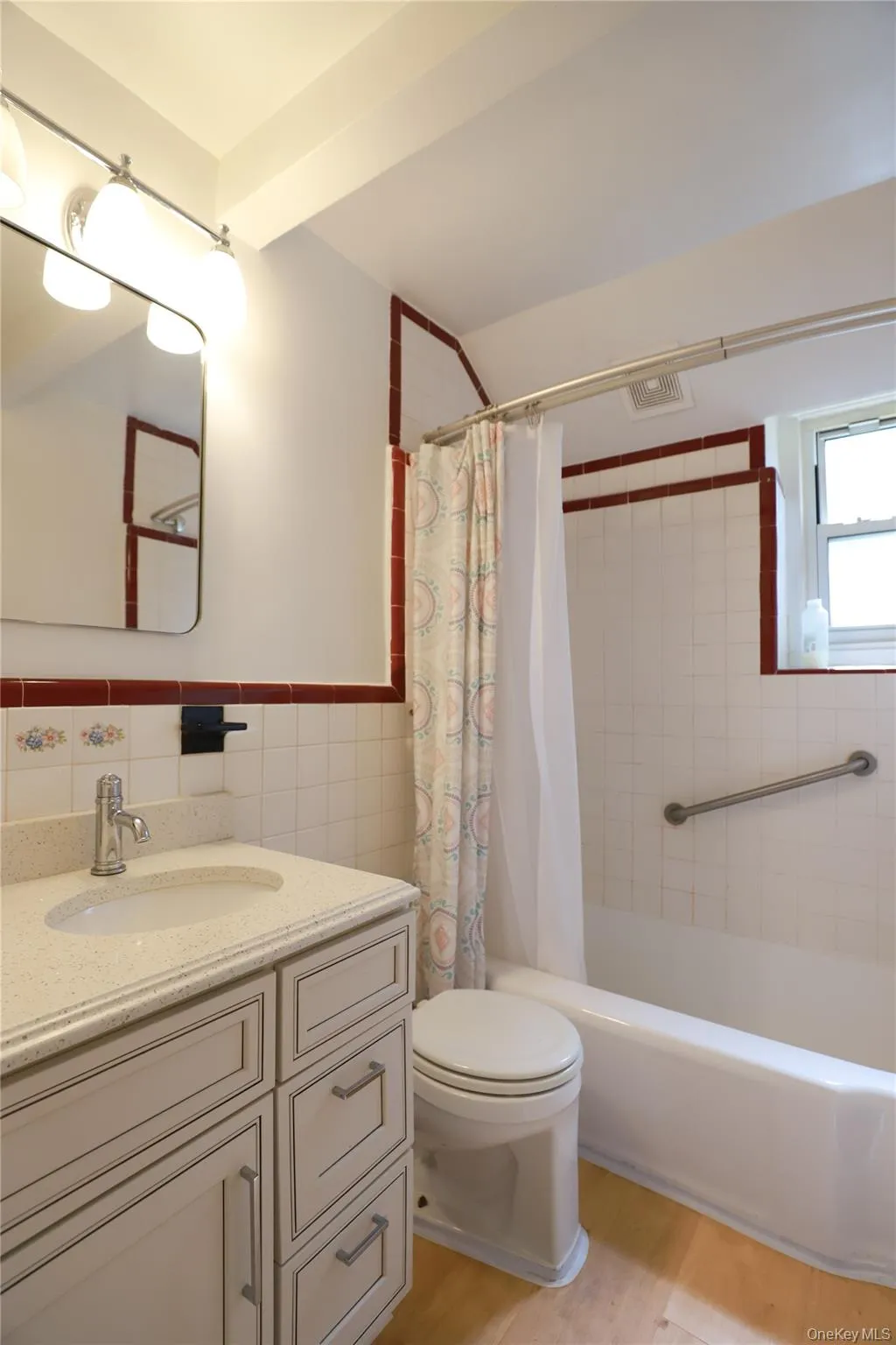 Bathroom featuring a single vanity with light countertop, wood-finish flooring, a full bathtub with grab bars Bathroom featuring a single vanity with light countertop, wood-finish flooring, a full bathtub with grab bars