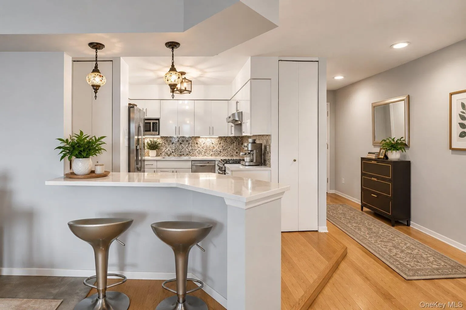 Kitchen featuring white cabinetry, stainless steel appliances, and a patterned tile backsplash Kitchen featuring white cabinetry, stainless steel appliances, and a patterned tile backsplash