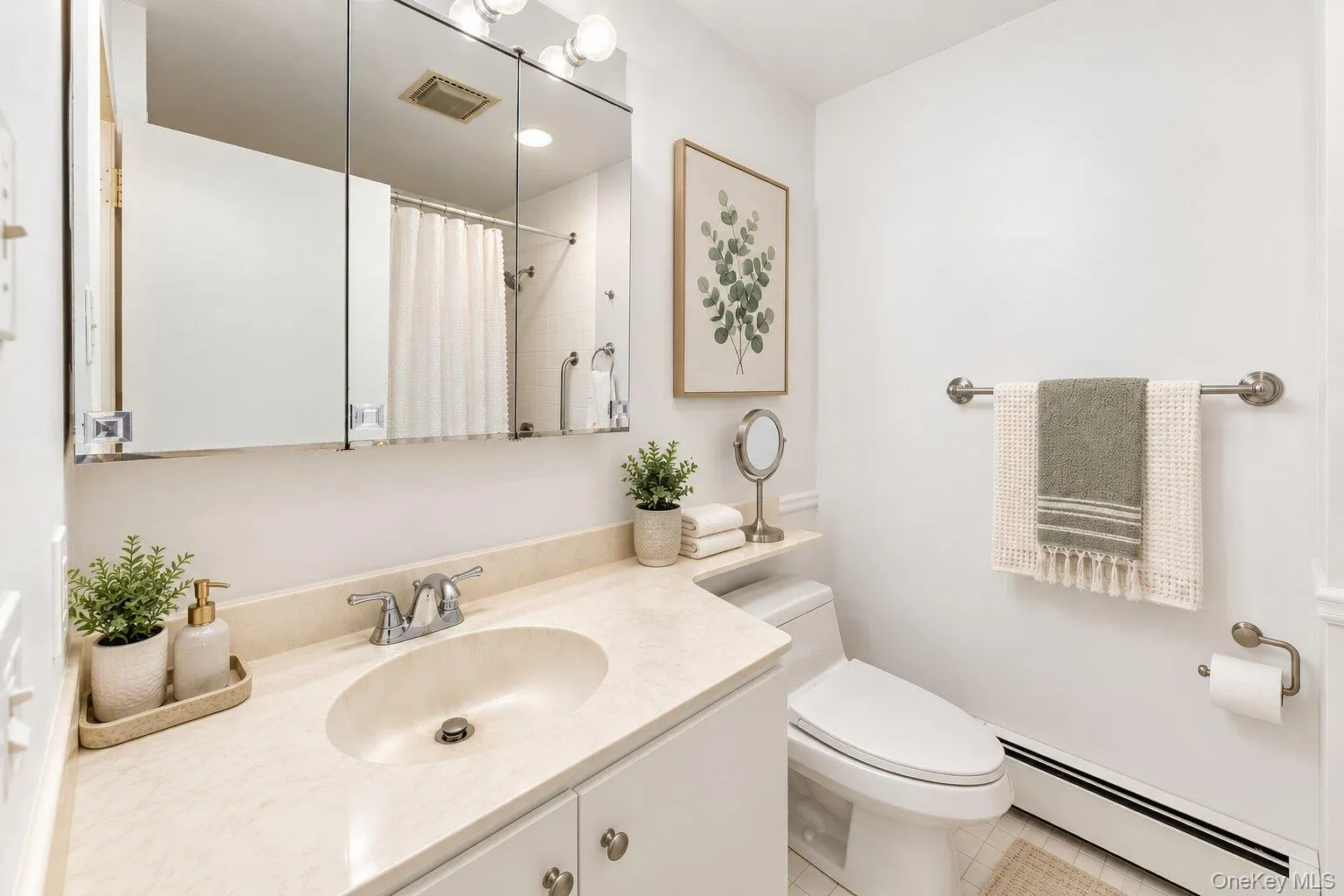 Vanity with an integrated sink and light-colored countertop, wall-mounted medicine cabinet with mirror, and a toilet with an adjacent shelf Vanity with an integrated sink and light-colored countertop, wall-mounted medicine cabinet with mirror, and a toilet with an adjacent shelf