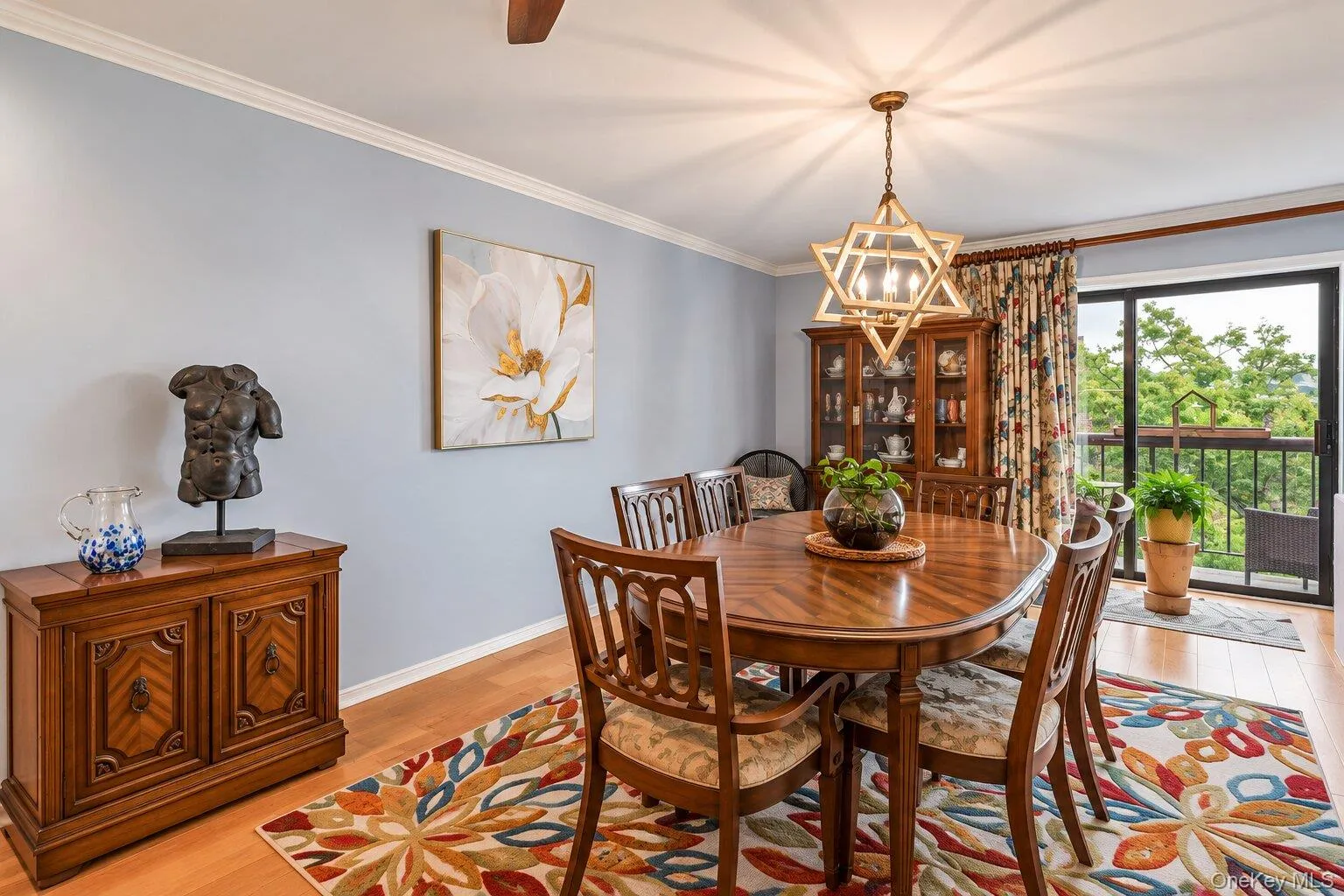 Light wood-finish flooring with crown molding and a prominent chandelier Light wood-finish flooring with crown molding and a prominent chandelier