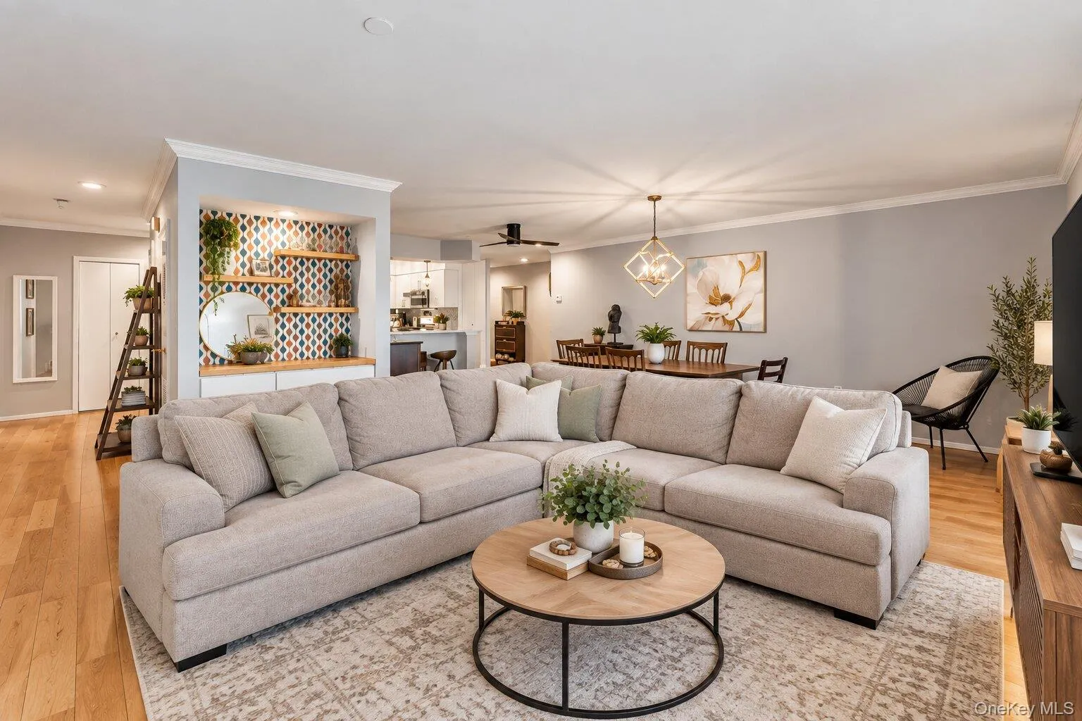 Hardwood-finish flooring throughout, recessed lighting, built-in shelving with patterned backing, crown molding, and a modern chandelier Hardwood-finish flooring throughout, recessed lighting, built-in shelving with patterned backing, crown molding, and a modern chandelier