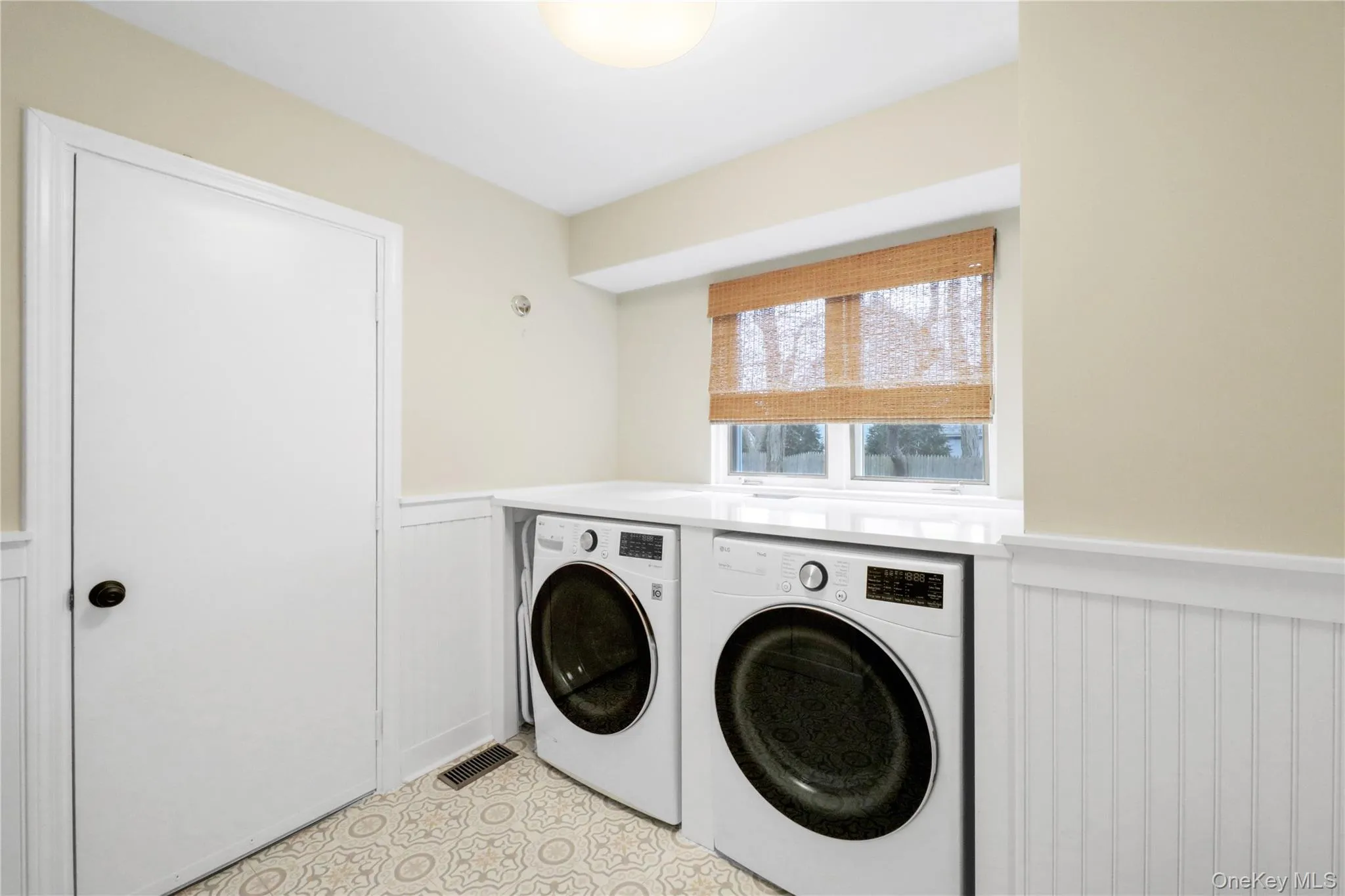 Laundry room featuring wainscoting, independent washer and dryer, and a decorative wall Laundry room featuring wainscoting, independent washer and dryer, and a decorative wall