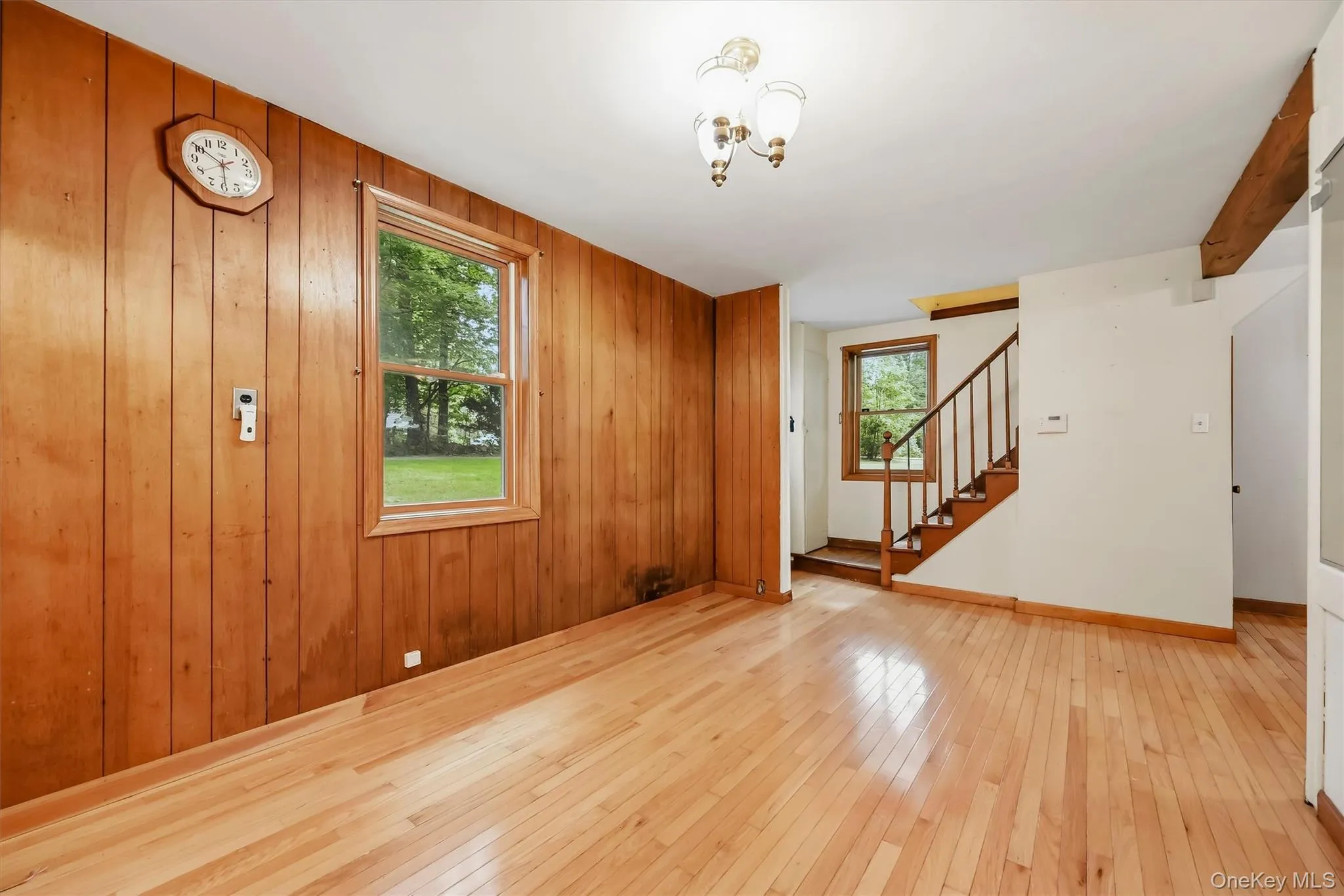 Hardwood flooring, wood paneling, wood-framed windows, and a classic chandelier Hardwood flooring, wood paneling, wood-framed windows, and a classic chandelier