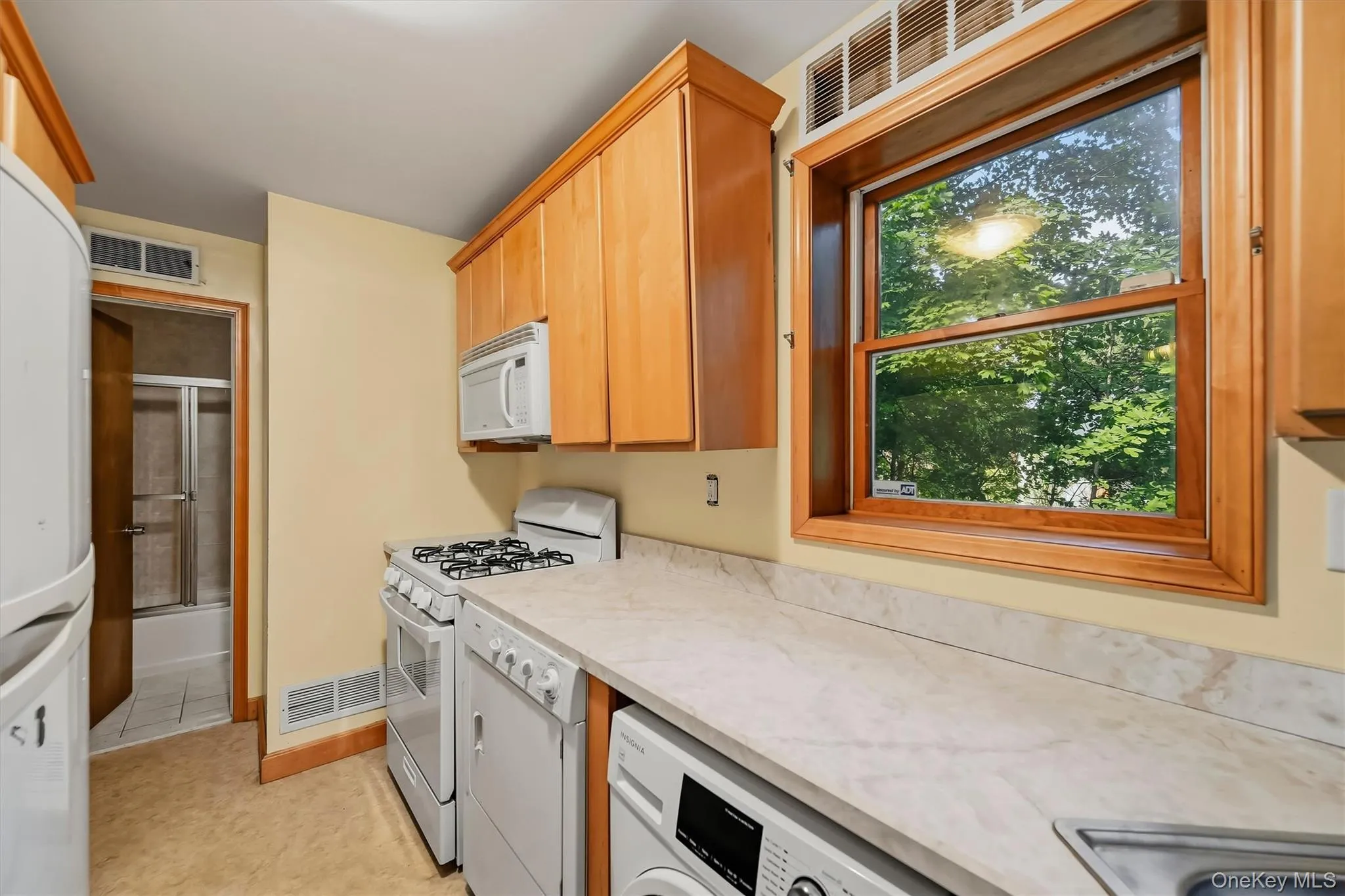 Kitchen featuring wood-finish cabinetry, solid surface countertops, a white gas range, and an integrated microwave Kitchen featuring wood-finish cabinetry, solid surface countertops, a white gas range, and an integrated microwave
