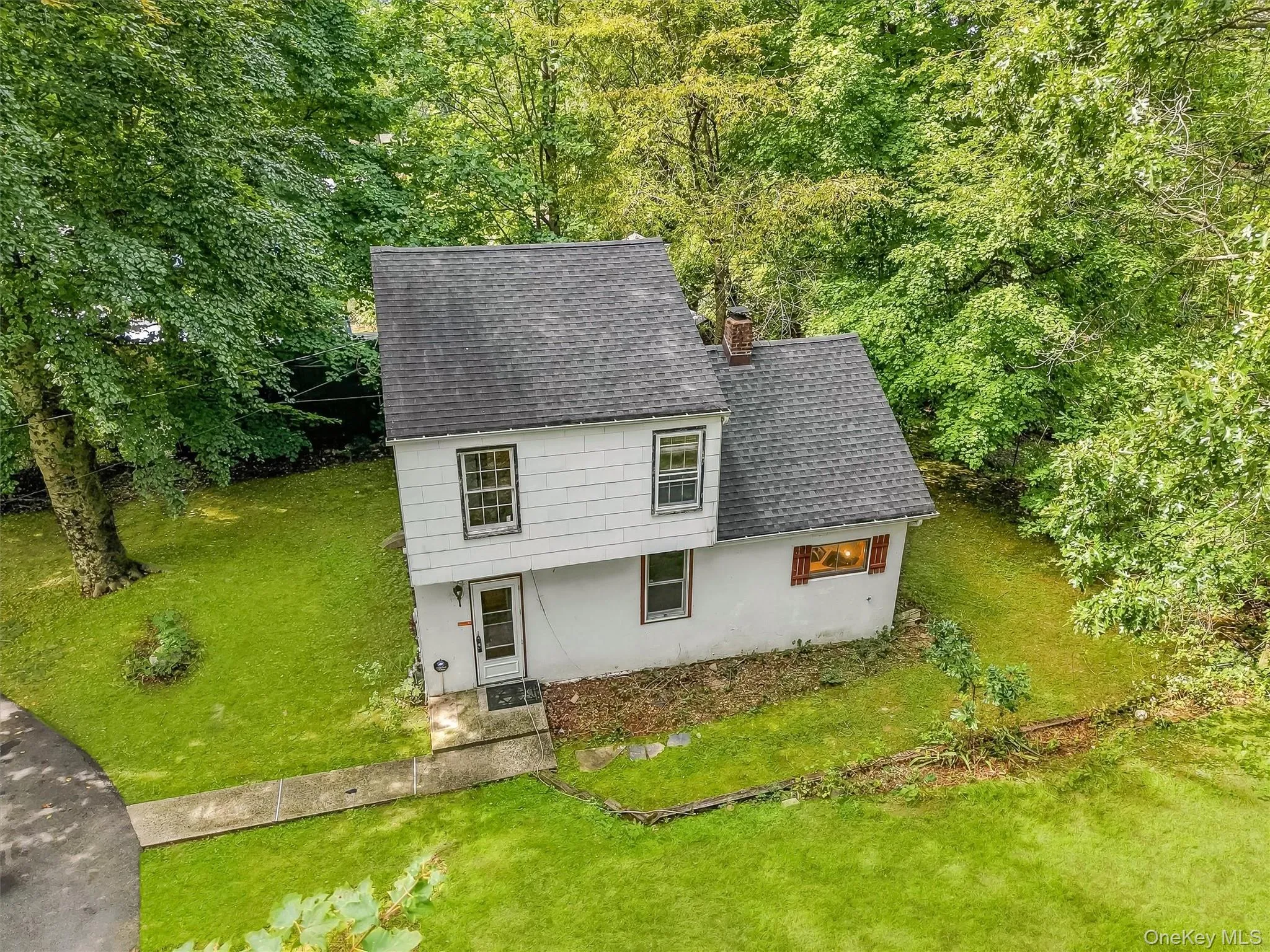 Two-story residence with white siding, dark shingle roof, and a red brick chimney Two-story residence with white siding, dark shingle roof, and a red brick chimney