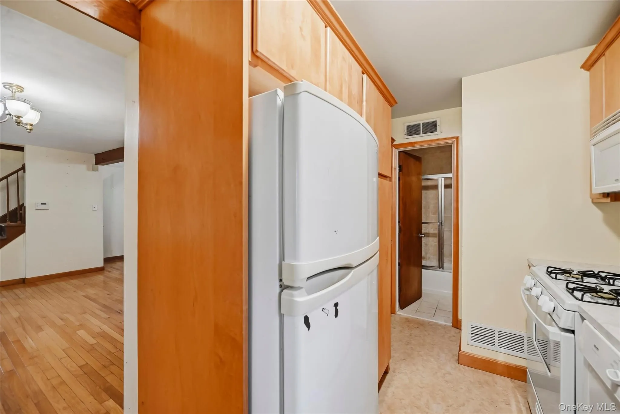 Kitchen featuring wood-finish cabinetry, a white refrigerator, and a white gas range with oven Kitchen featuring wood-finish cabinetry, a white refrigerator, and a white gas range with oven