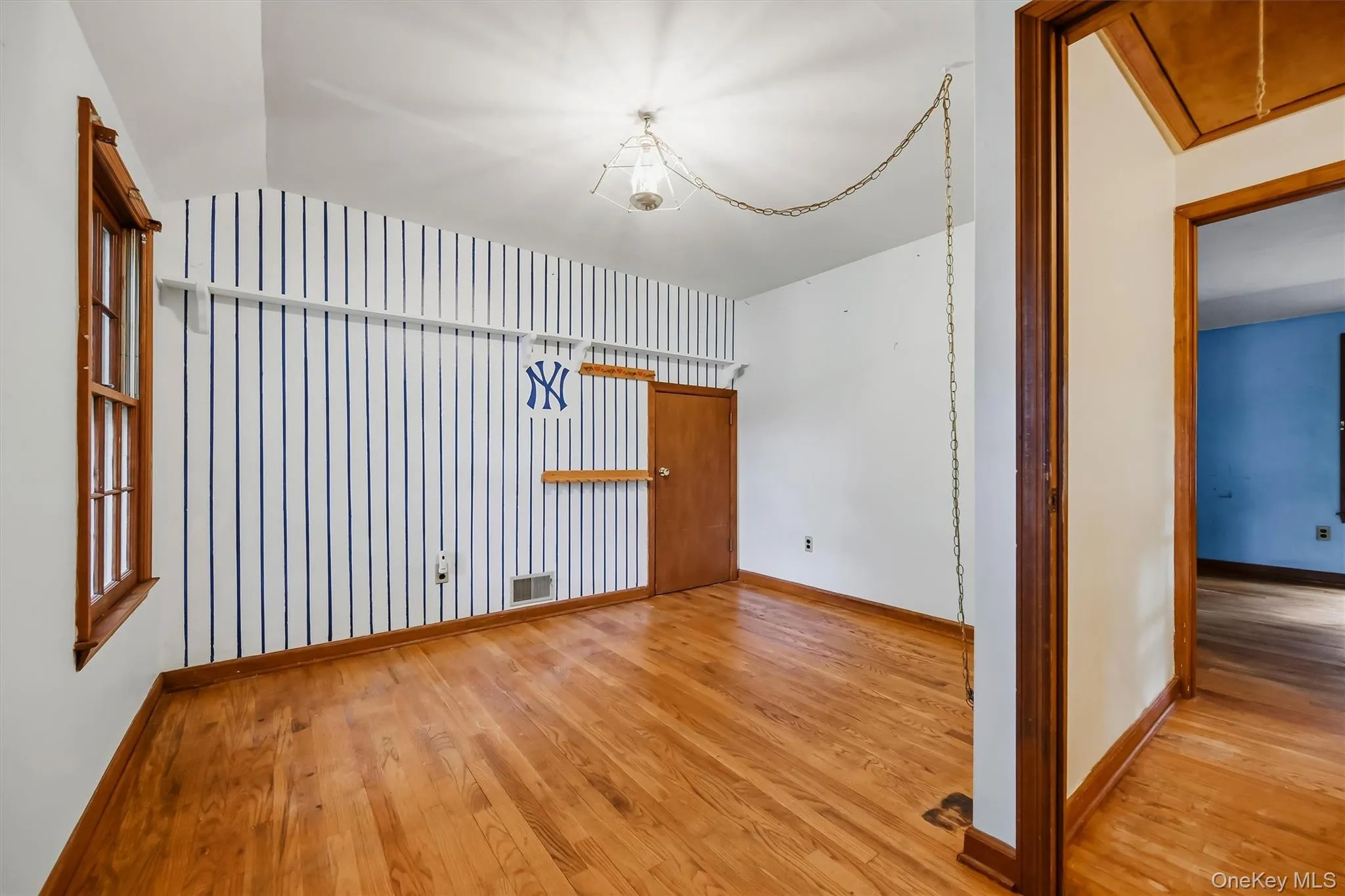 Hardwood flooring throughout, a fixed window with wood trim, and a fixed ceiling light fixture Hardwood flooring throughout, a fixed window with wood trim, and a fixed ceiling light fixture