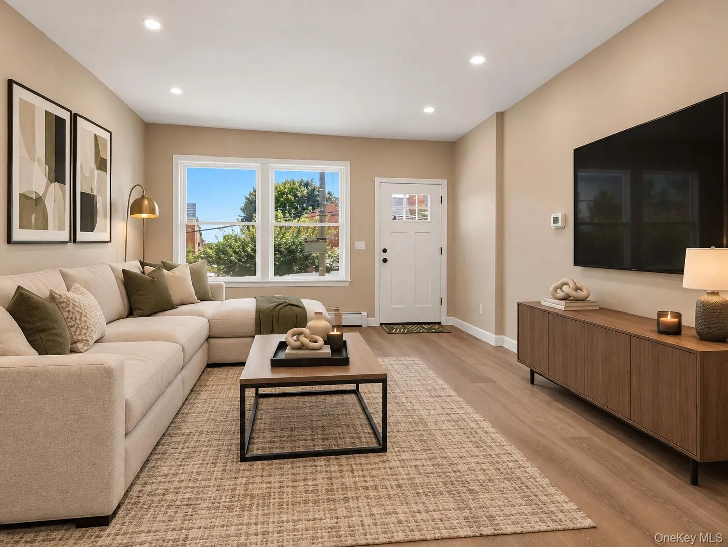 Recessed lighting illuminates the open living space, featuring wood-finish flooring and a multi-pane entry door Recessed lighting illuminates the open living space, featuring wood-finish flooring and a multi-pane entry door