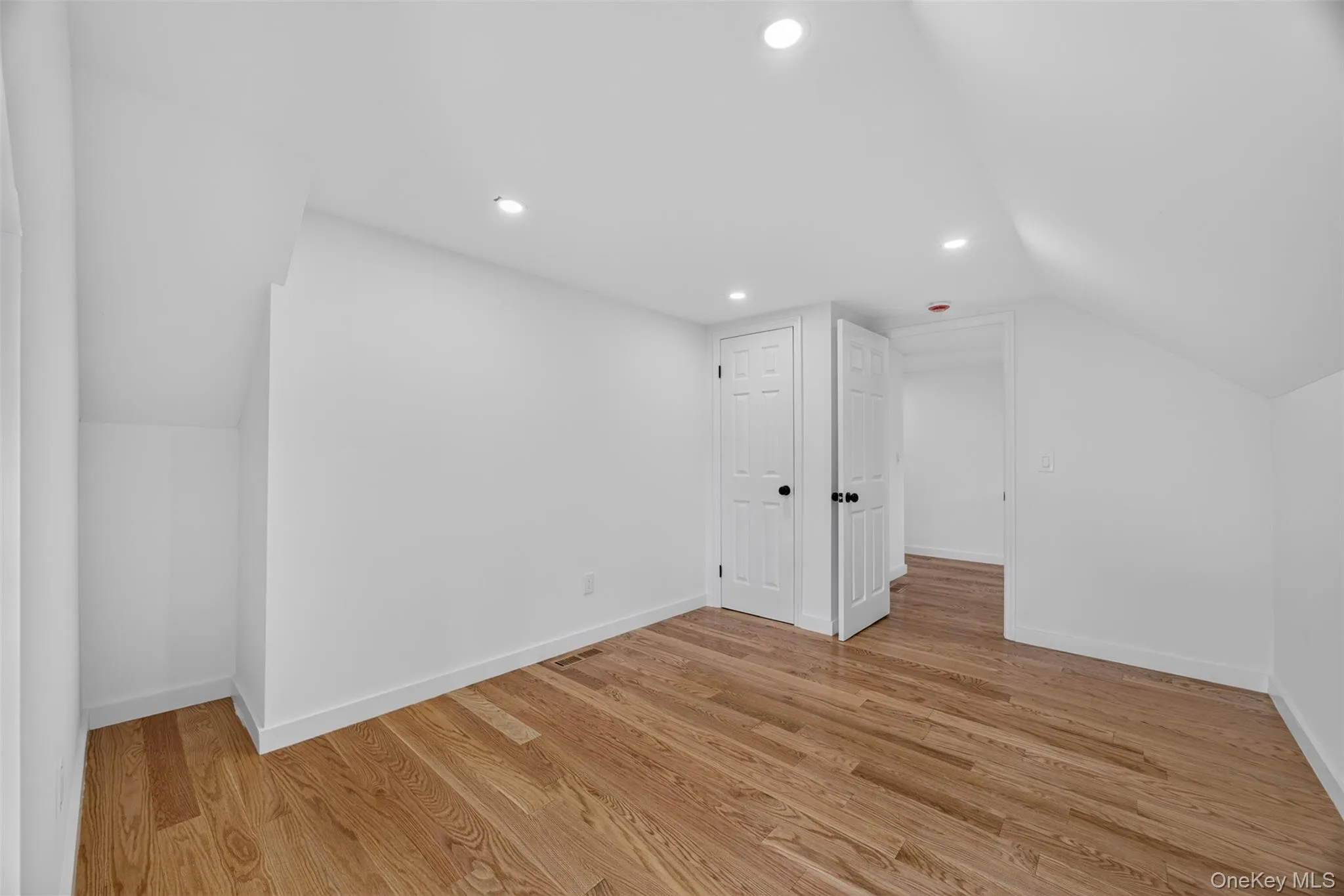 Hardwood flooring, recessed lighting, white paneled doors, and angled ceilings Hardwood flooring, recessed lighting, white paneled doors, and angled ceilings