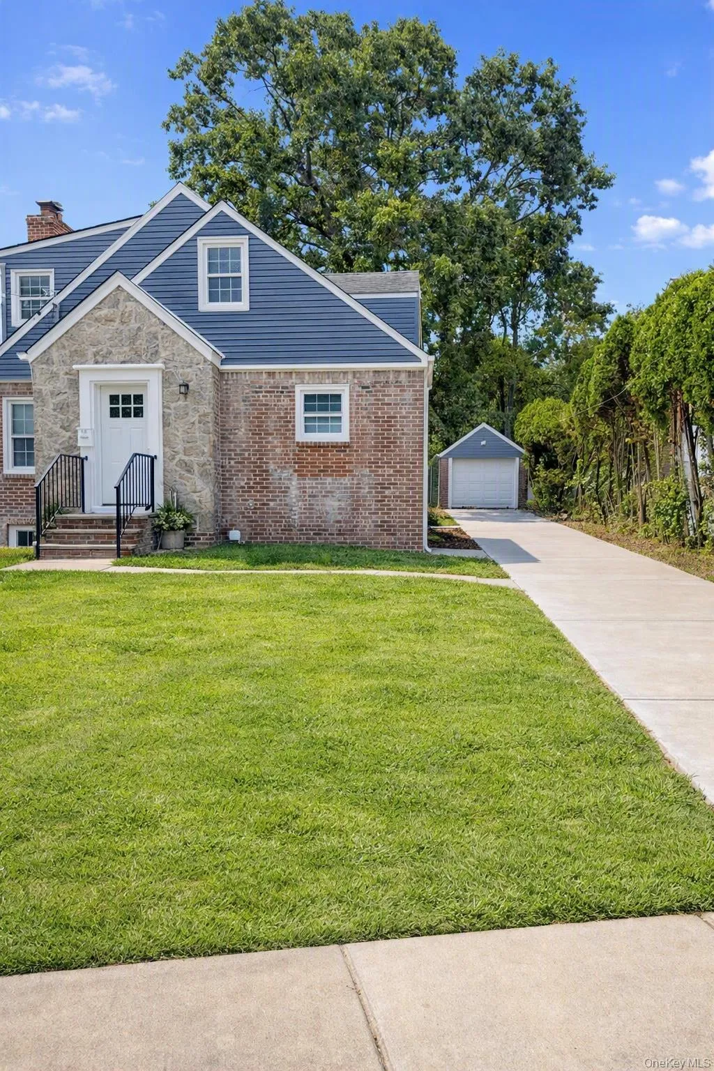 Exterior featuring a combination of stone and brick masonry, blue siding, a detached garage, and a concrete driveway Exterior featuring a combination of stone and brick masonry, blue siding, a detached garage, and a concrete driveway