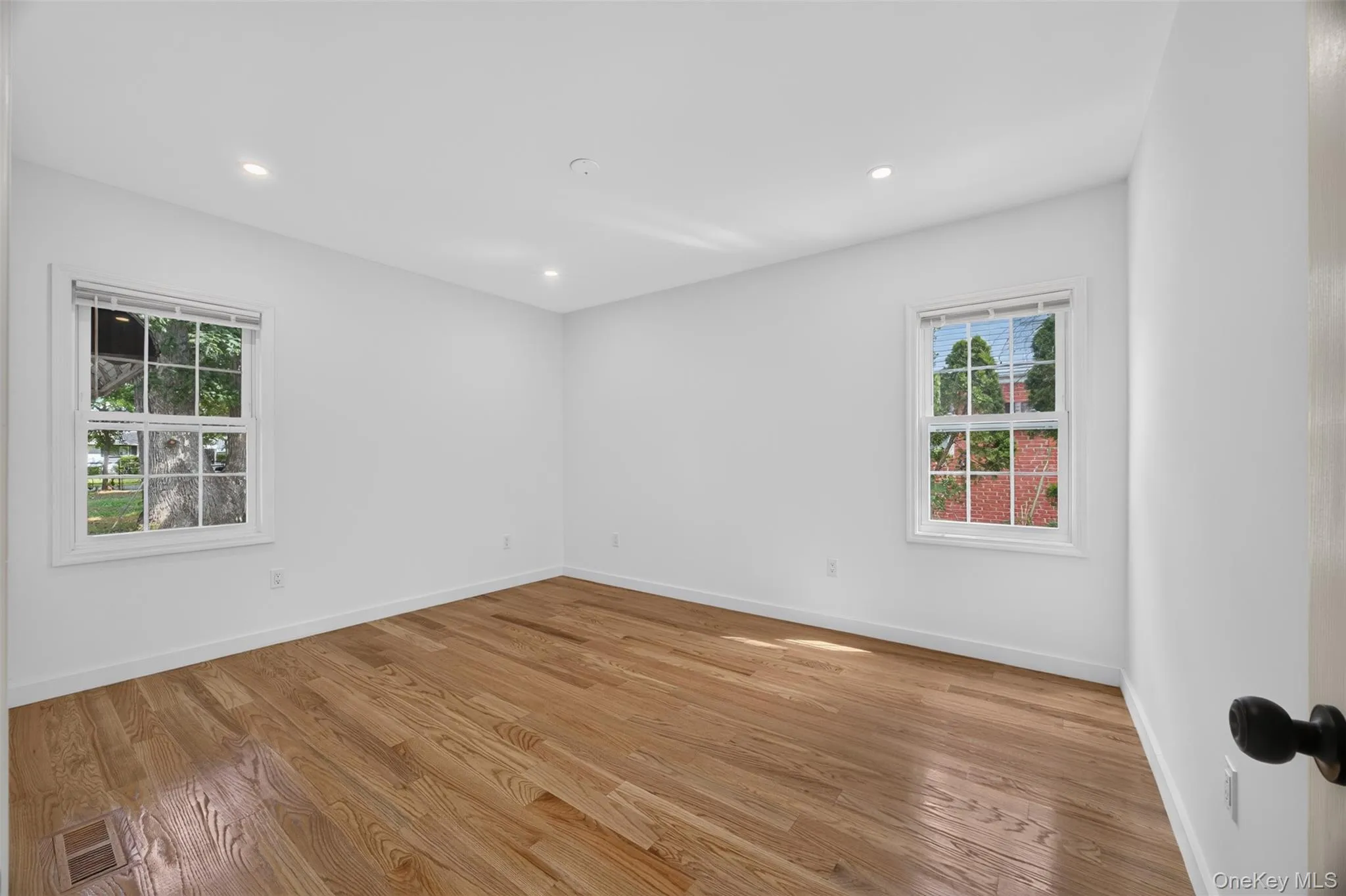 Hardwood flooring, two windows with white trim, recessed lighting, and white walls Hardwood flooring, two windows with white trim, recessed lighting, and white walls