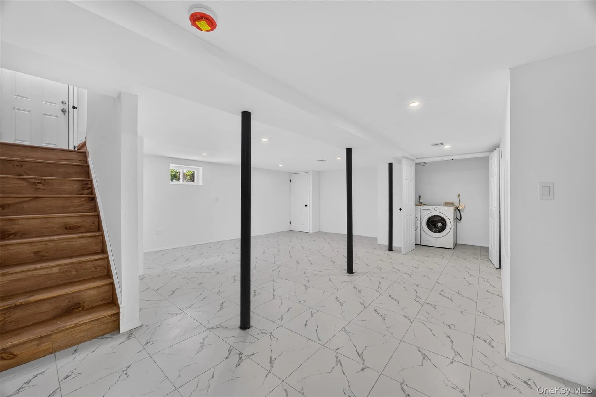 Spacious lower level featuring marble-look tile flooring, recessed lighting, wood-finish stairs, and a built-in laundry area Spacious lower level featuring marble-look tile flooring, recessed lighting, wood-finish stairs, and a built-in laundry area