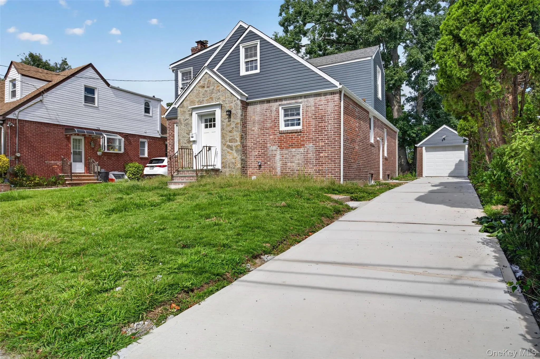 Brick and stone exterior with siding accents, front entry with wrought iron railing, concrete driveway, and detached garage Brick and stone exterior with siding accents, front entry with wrought iron railing, concrete driveway, and detached garage
