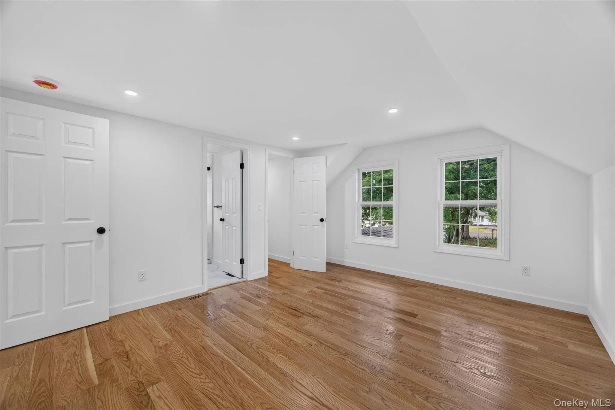 Wood-finish flooring, recessed lighting, white panel doors, and sloped ceiling Wood-finish flooring, recessed lighting, white panel doors, and sloped ceiling