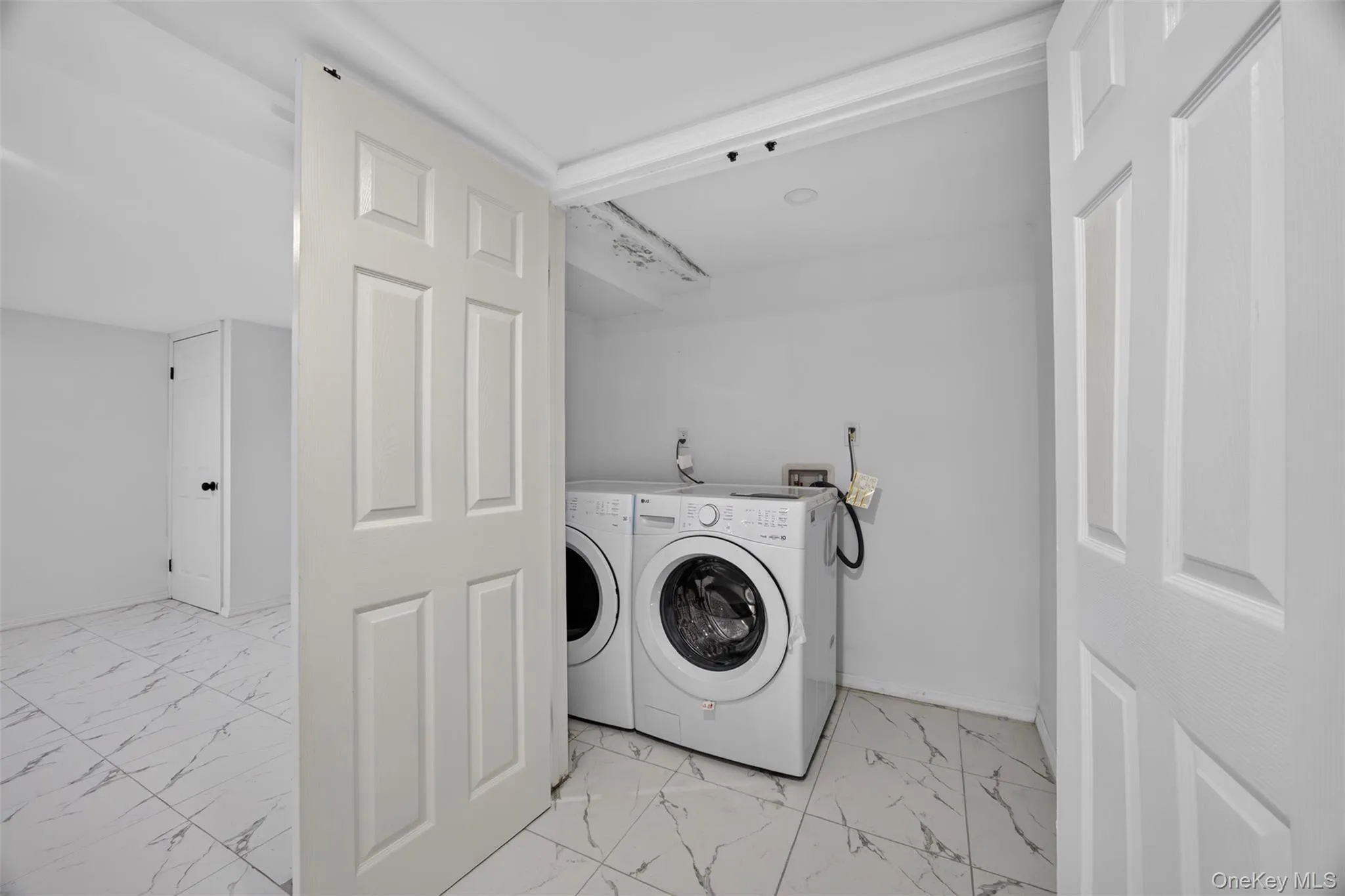 White paneled interior doors, tile flooring with marble-look veining, and white walls White paneled interior doors, tile flooring with marble-look veining, and white walls
