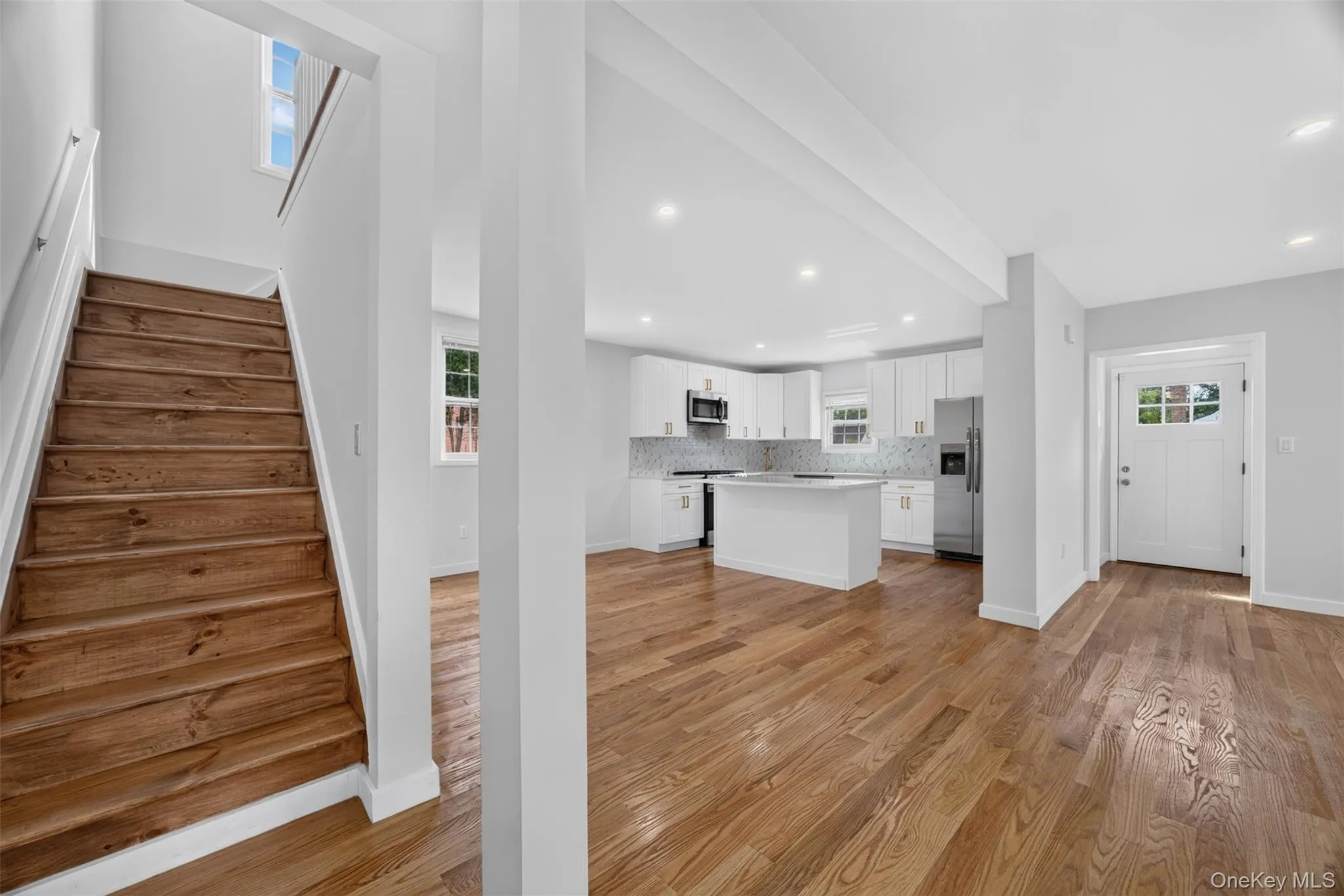 Hardwood flooring throughout, white kitchen cabinetry, stainless steel appliances, kitchen island, and recessed lighting Hardwood flooring throughout, white kitchen cabinetry, stainless steel appliances, kitchen island, and recessed lighting
