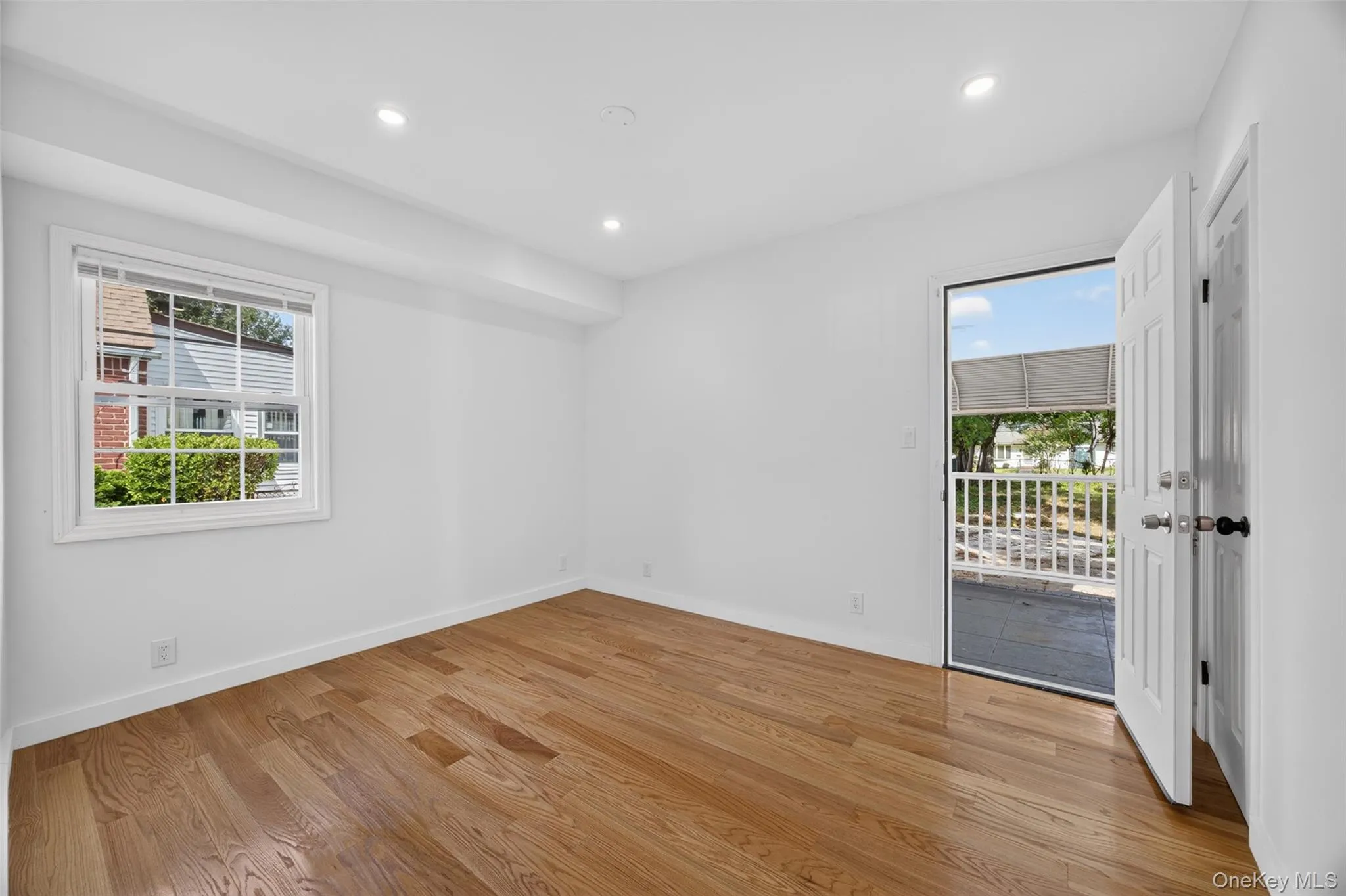 Wood-finish flooring, recessed lighting, and a white paneled door leading to an outdoor area Wood-finish flooring, recessed lighting, and a white paneled door leading to an outdoor area