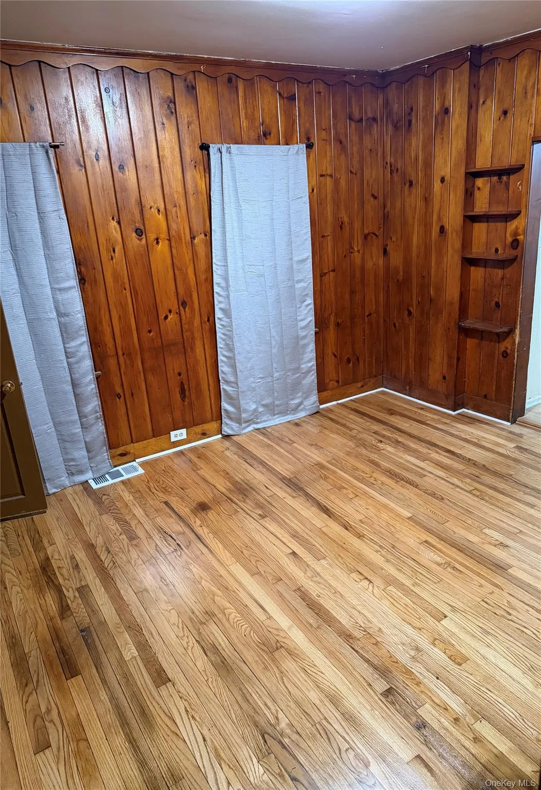 Empty room featuring light wood-style flooring and wooden walls Empty room featuring light wood-style flooring and wooden walls