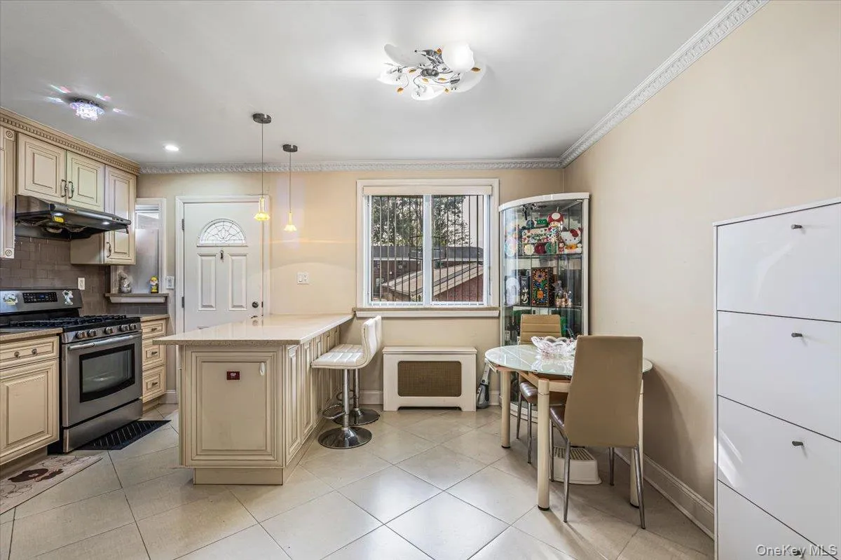 Kitchen featuring cream-colored cabinetry, stainless steel appliances, a light-toned countertop, and tile flooring Kitchen featuring cream-colored cabinetry, stainless steel appliances, a light-toned countertop, and tile flooring