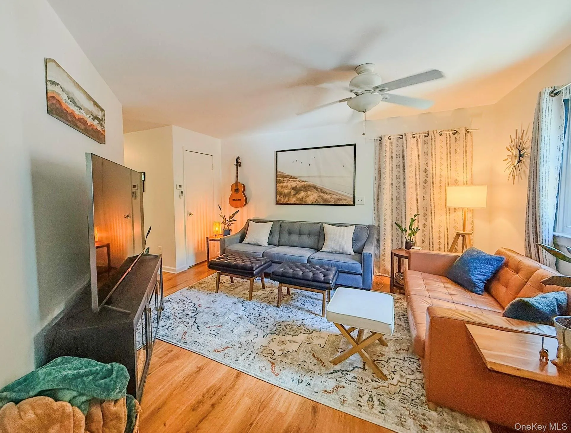 Upper Apartment Living Room Hardwood-style flooring throughout, ceiling fan with integrated lighting, and multiple windows with vertical blinds Upper Apartment Living Room Hardwood-style flooring throughout, ceiling fan with integrated lighting, and multiple windows with vertical blinds