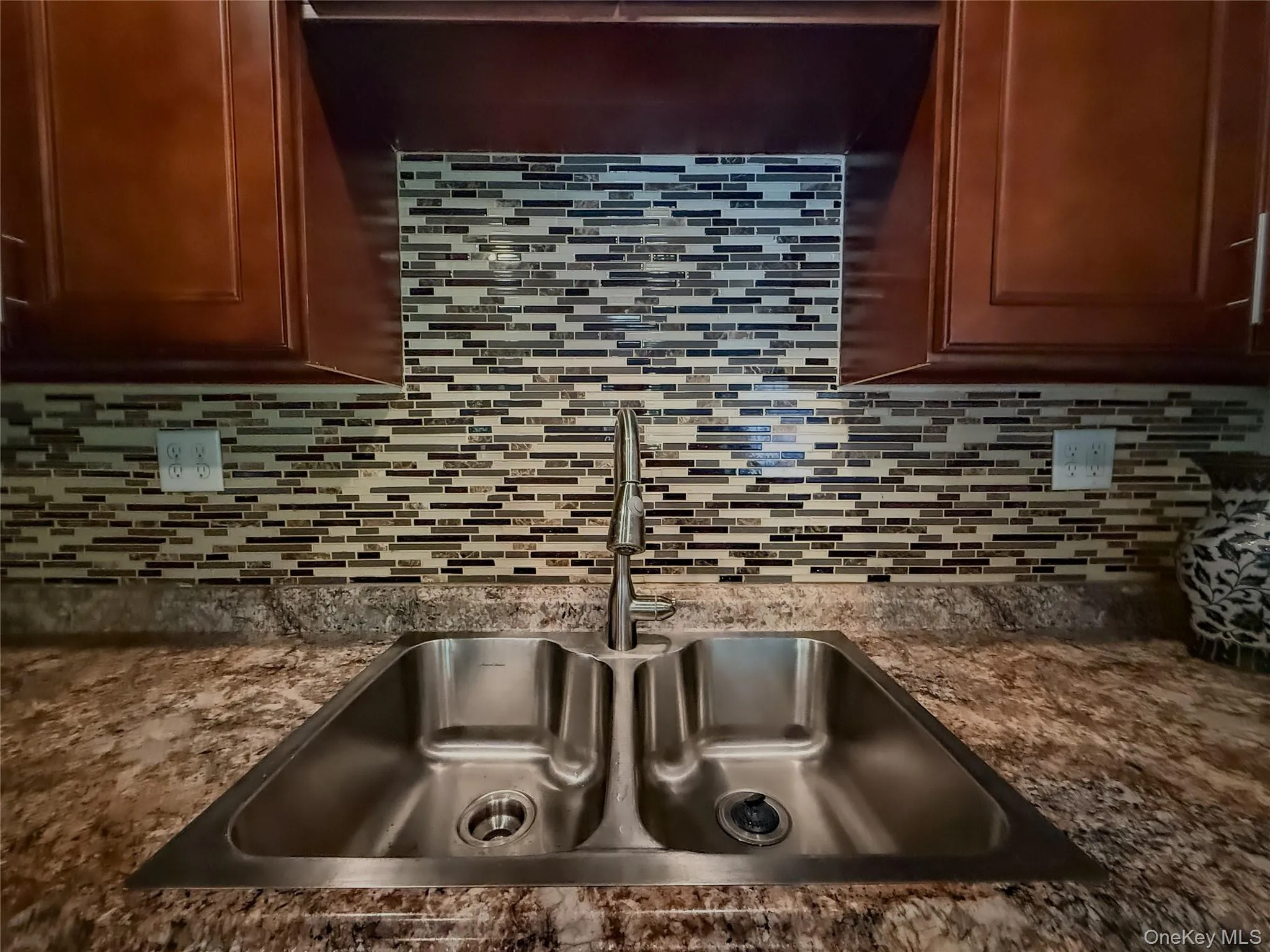 Lower Apartment Kitchen featuring wood-finish cabinetry, stainless steel appliances, patterned backsplash, and stainless sink Lower Apartment Kitchen featuring wood-finish cabinetry, stainless steel appliances, patterned backsplash, and stainless sink