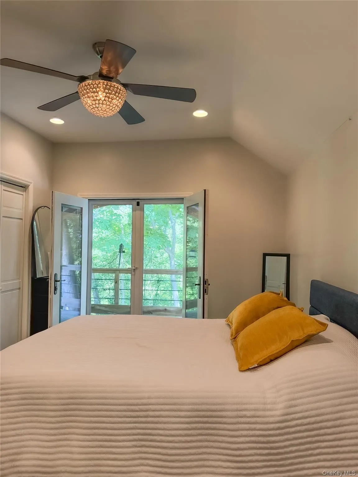 Cottage bedroom with vaulted ceiling with recessed lighting, a decorative ceiling fan, and French doors that leads to private deck Cottage bedroom with vaulted ceiling with recessed lighting, a decorative ceiling fan, and French doors that leads to private deck