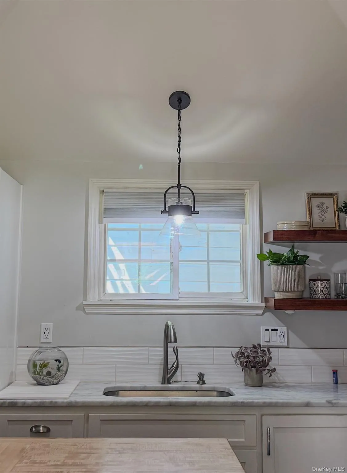 Cottage kitchen featuring a central island with white shaker cabinetry, stainless steel appliances, and open wood shelving Cottage kitchen featuring a central island with white shaker cabinetry, stainless steel appliances, and open wood shelving