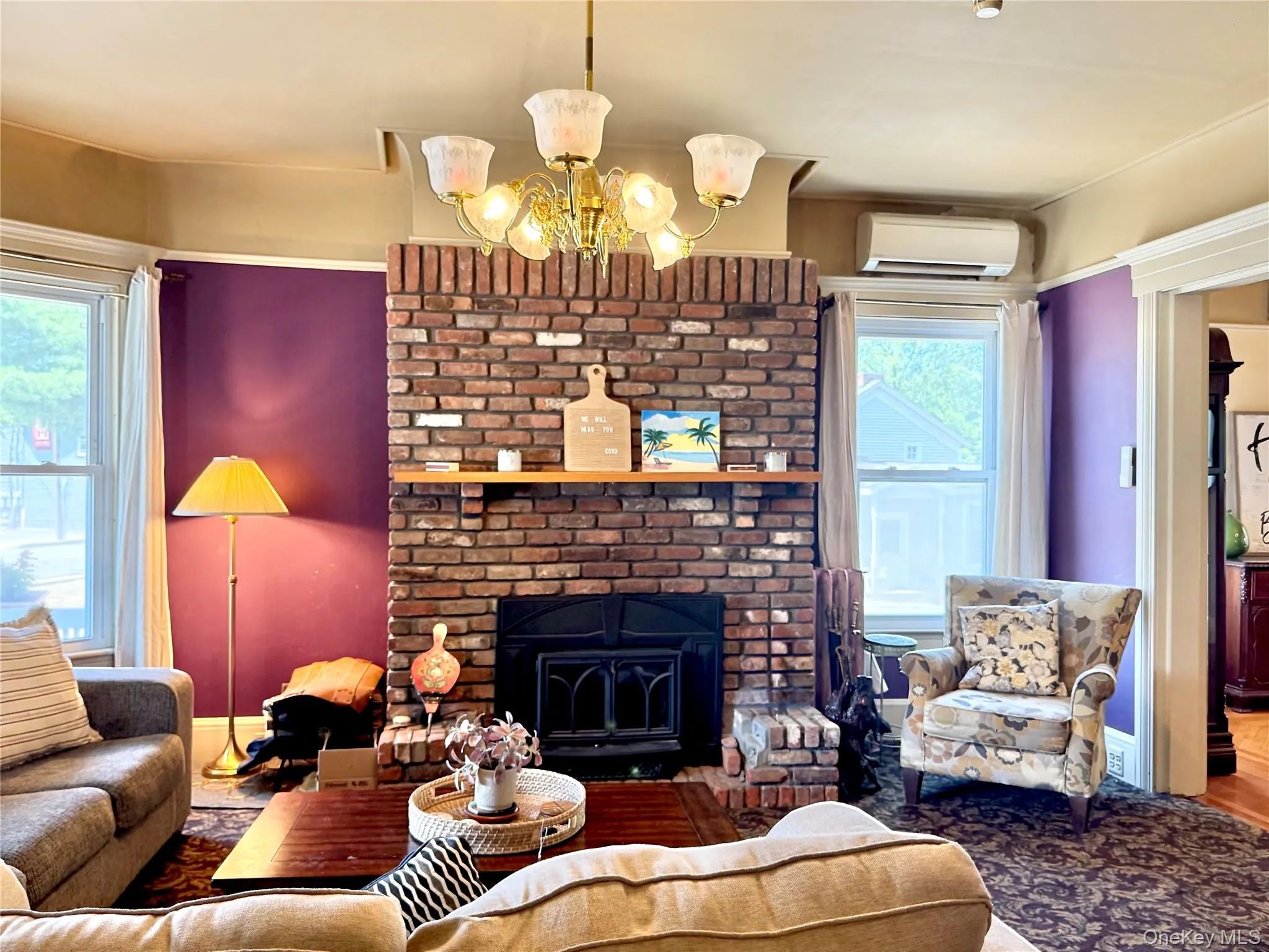 Main House Living Room Brick fireplace with two large windows Main House Living Room Brick fireplace with two large windows
