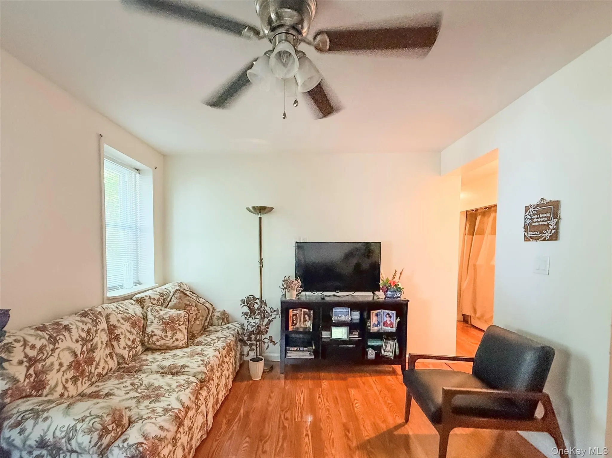 Lower Apartment Living Room hardwood-style flooring throughout, ceiling fan with integrated lighting, and multiple windows with vertical blinds Lower Apartment Living Room hardwood-style flooring throughout, ceiling fan with integrated lighting, and multiple windows with vertical blinds