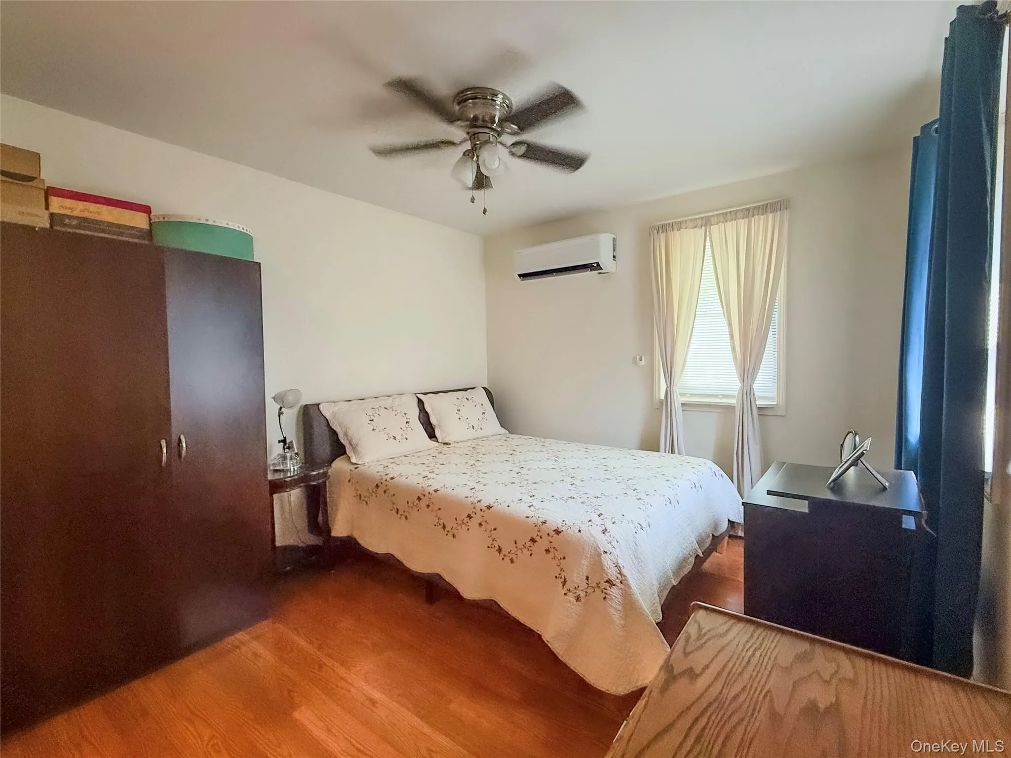 Lower apt bedroom Hardwood flooring, ceiling fan, and window with curtains Lower apt bedroom Hardwood flooring, ceiling fan, and window with curtains