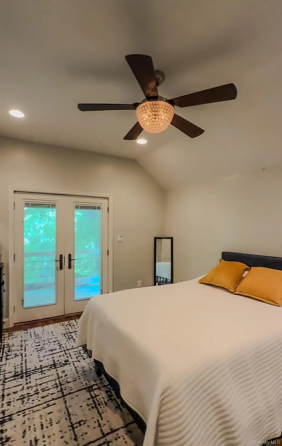 Cottage bedroom with vaulted ceiling with recessed lighting, a decorative ceiling fan, and French doors that leads to private deck Cottage bedroom with vaulted ceiling with recessed lighting, a decorative ceiling fan, and French doors that leads to private deck
