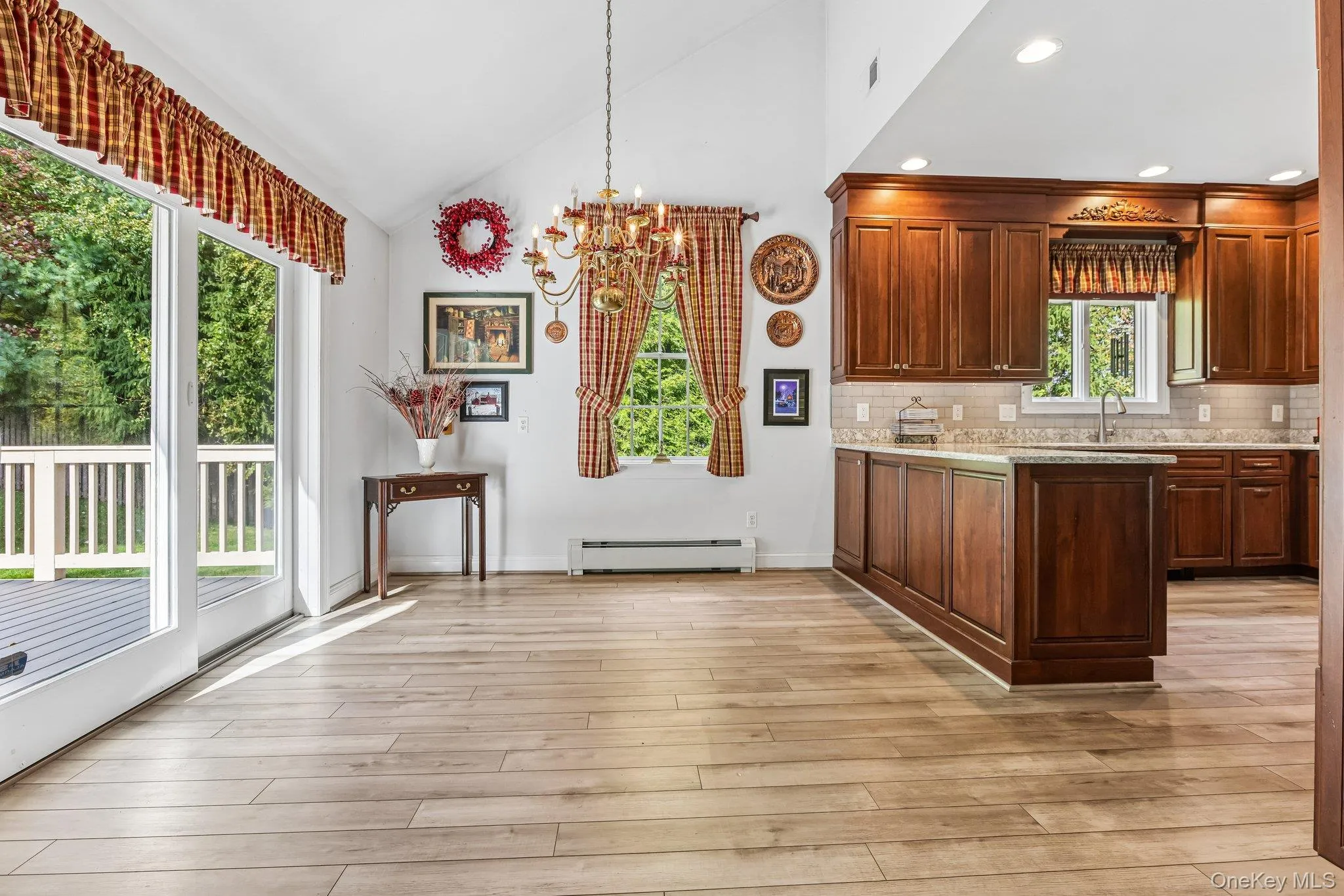 Varnished wood-finish flooring, vaulted ceiling, built-in recessed lighting, wood cabinetry with countertop, and sliding glass door to exterior decking Varnished wood-finish flooring, vaulted ceiling, built-in recessed lighting, wood cabinetry with countertop, and sliding glass door to exterior decking