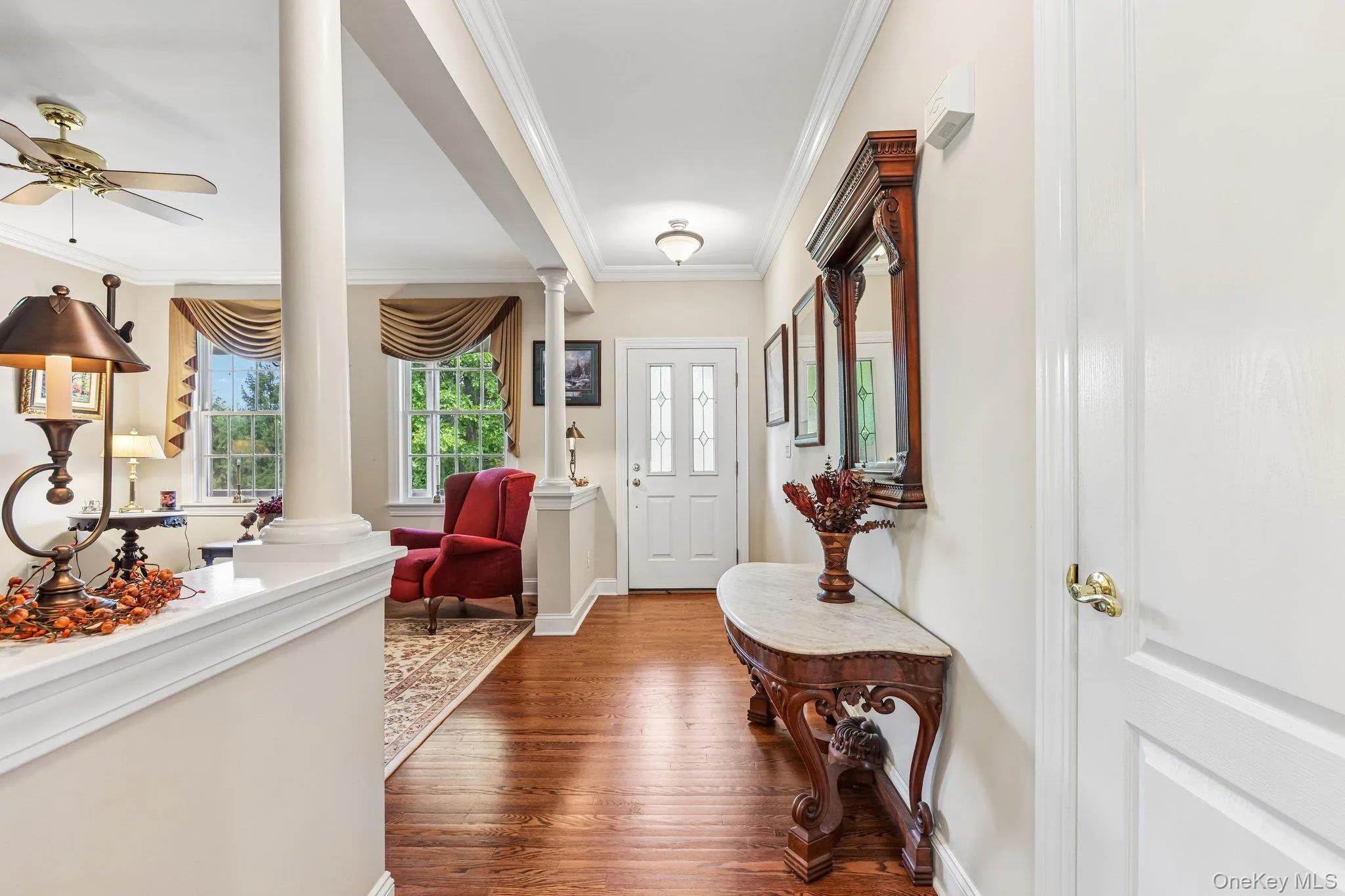 Hardwood flooring, decorative columns, crown molding, transom window above entry, and a ceiling fan Hardwood flooring, decorative columns, crown molding, transom window above entry, and a ceiling fan