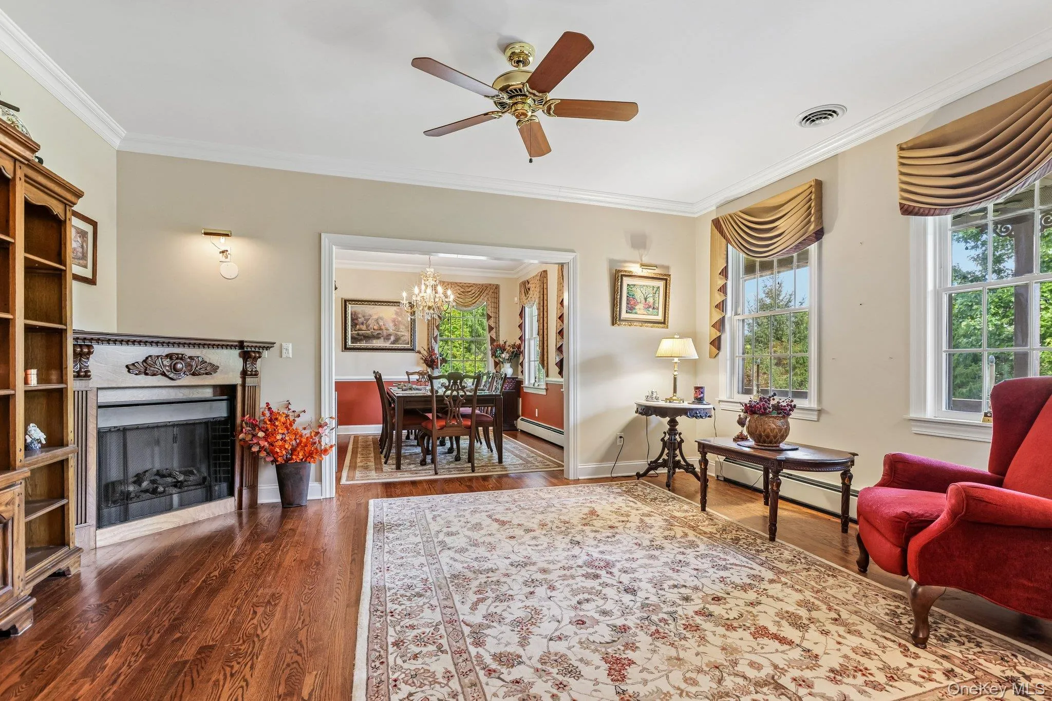 Hardwood flooring, decorative fireplace, crown molding, and a ceiling fan with integrated lighting Hardwood flooring, decorative fireplace, crown molding, and a ceiling fan with integrated lighting