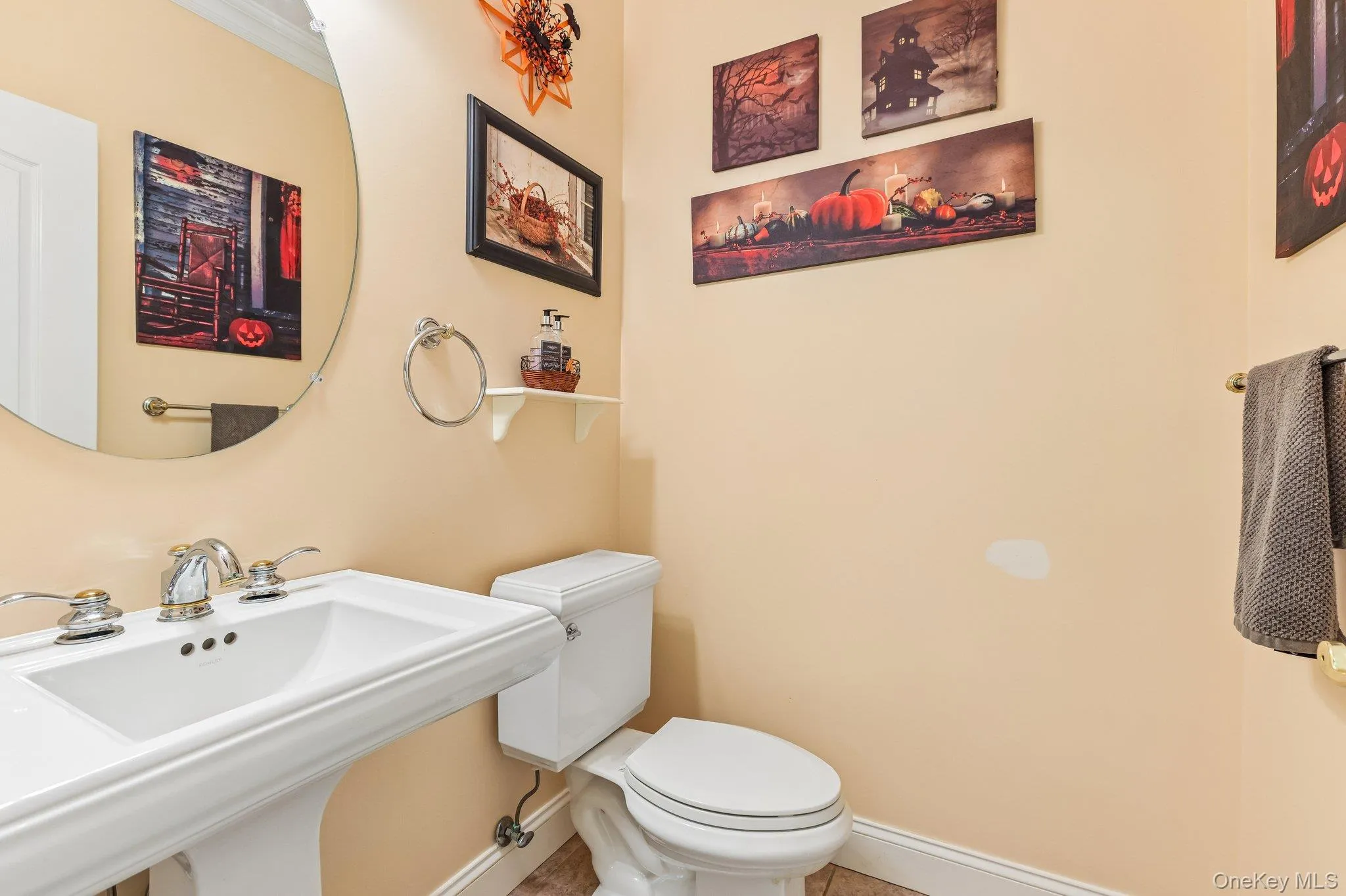 Pedestal sink with chrome fixtures, round wall-mounted mirror, and white toilet Pedestal sink with chrome fixtures, round wall-mounted mirror, and white toilet