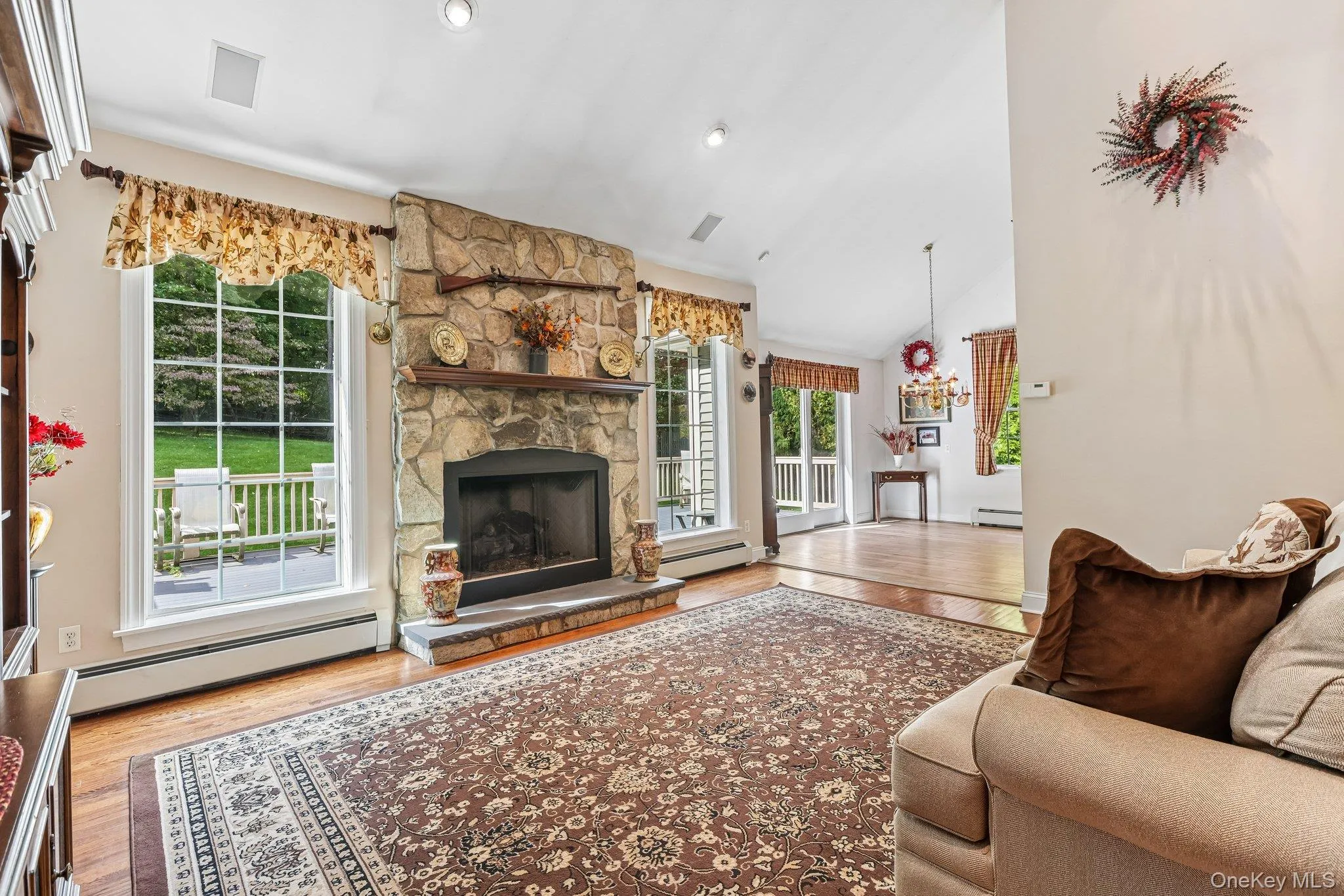 Vaulted ceiling with recessed lighting, stone fireplace with hearth and wood mantel, large pane windows, and wood-finish flooring Vaulted ceiling with recessed lighting, stone fireplace with hearth and wood mantel, large pane windows, and wood-finish flooring