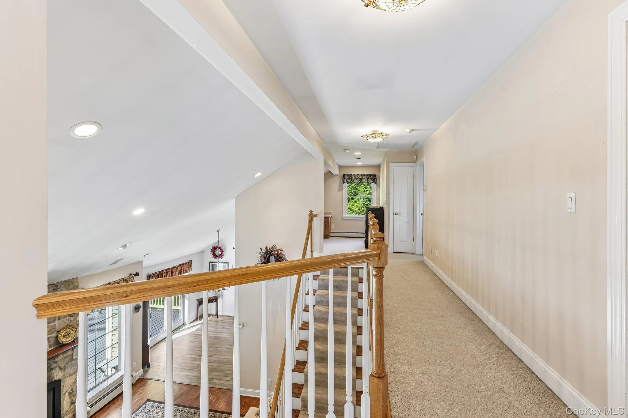 Carpeted hallway with flush-mount lighting, wood handrails, and white balusters Carpeted hallway with flush-mount lighting, wood handrails, and white balusters
