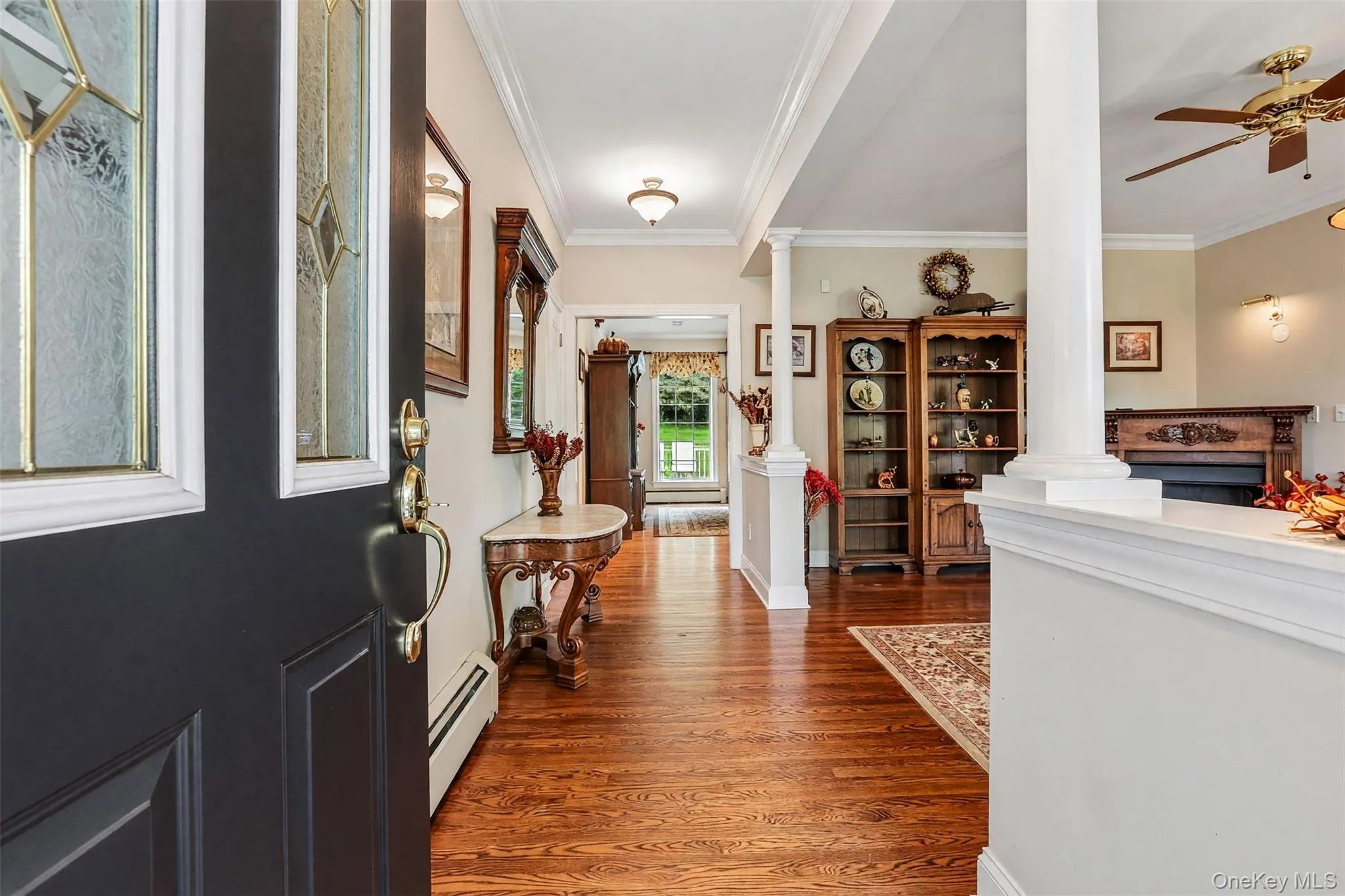 Hardwood flooring, decorative columns, crown molding, a built-in fireplace, and a ceiling fan Hardwood flooring, decorative columns, crown molding, a built-in fireplace, and a ceiling fan