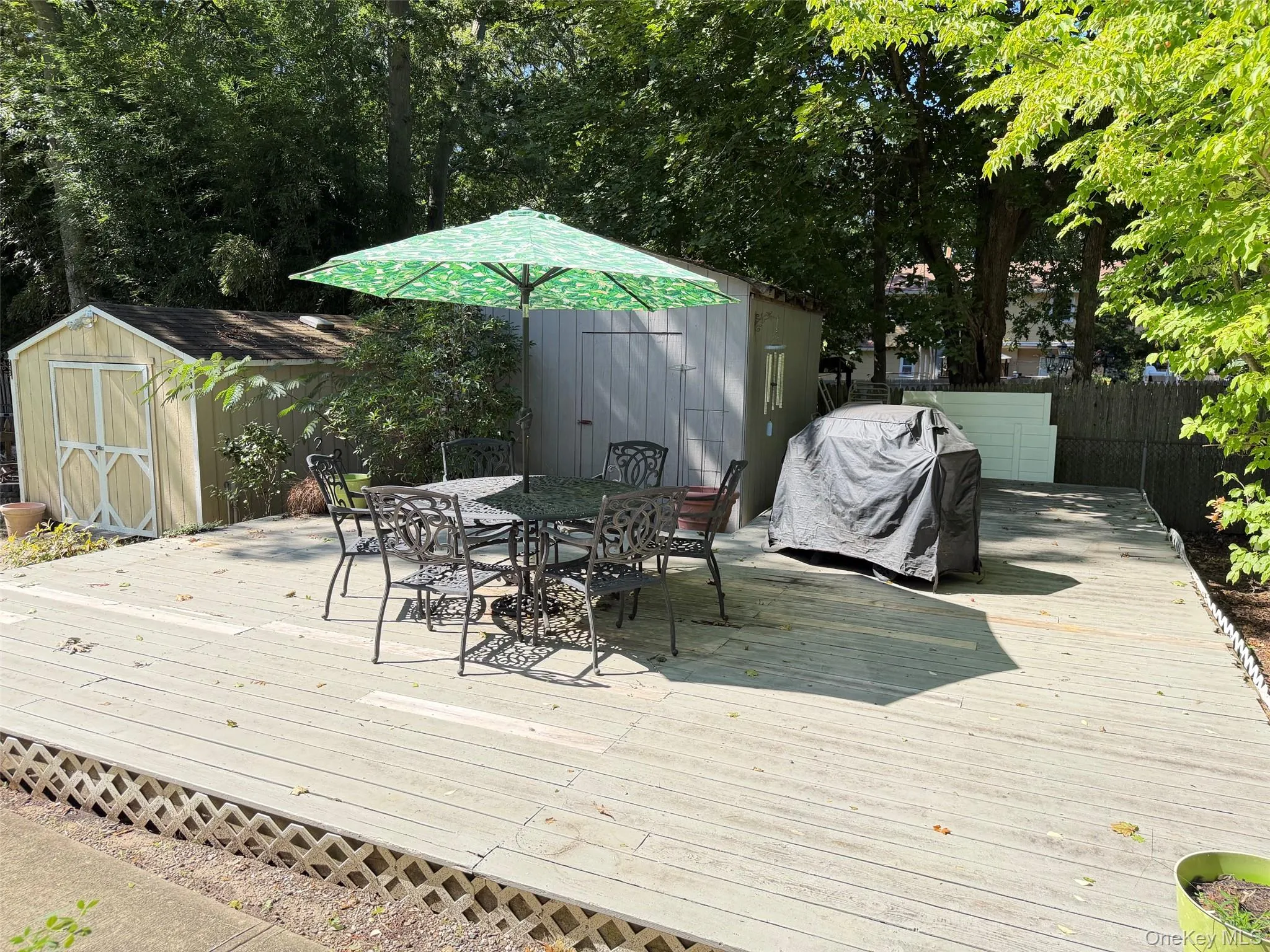 Expansive outdoor deck with lattice skirting, featuring two storage sheds Expansive outdoor deck with lattice skirting, featuring two storage sheds