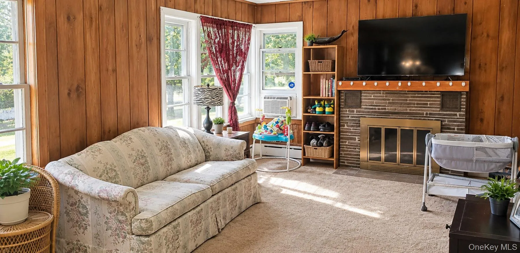Wood-paneled walls, multiple windows, and a stone-faced fireplace with a mantel Wood-paneled walls, multiple windows, and a stone-faced fireplace with a mantel