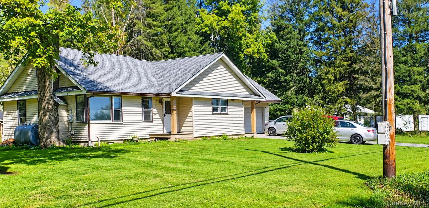 Siding exterior with a gabled roofline, mature tree, and an attached carport Siding exterior with a gabled roofline, mature tree, and an attached carport