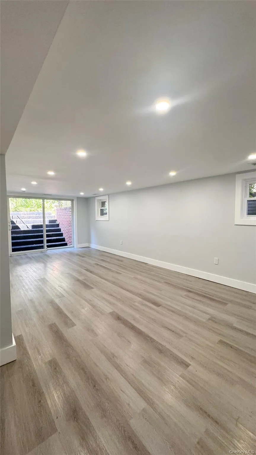 Spacious room featuring wood-finish flooring, recessed lighting, and light-toned walls Spacious room featuring wood-finish flooring, recessed lighting, and light-toned walls