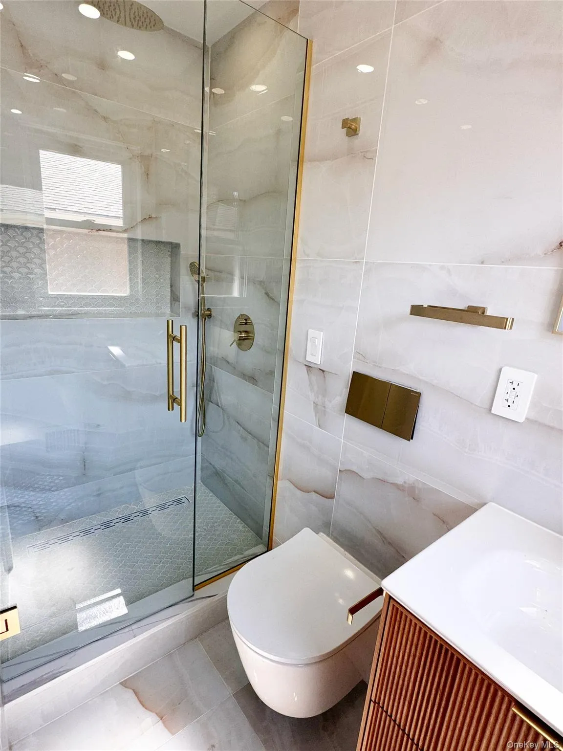 Glass-enclosed shower with gold-finish hardware, rainfall shower head, and tiled walls Glass-enclosed shower with gold-finish hardware, rainfall shower head, and tiled walls