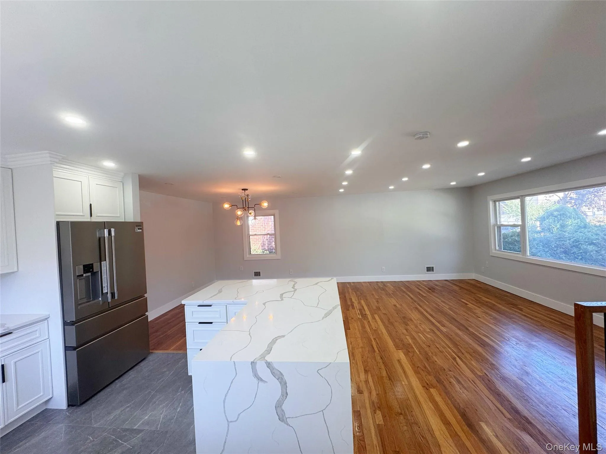 Gourmet kitchen with an expansive island, white cabinetry, and stainless steel refrigerator Gourmet kitchen with an expansive island, white cabinetry, and stainless steel refrigerator