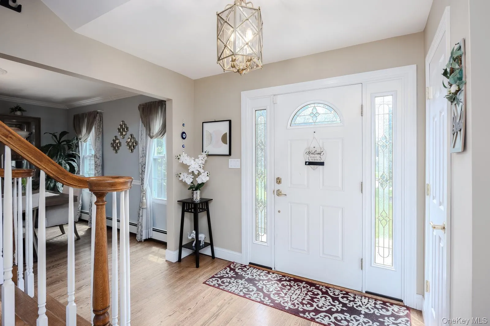 Foyer featuring a paneled entry door with an arched transom, sidelights with decorative glass, and wood-finish flooring Foyer featuring a paneled entry door with an arched transom, sidelights with decorative glass, and wood-finish flooring